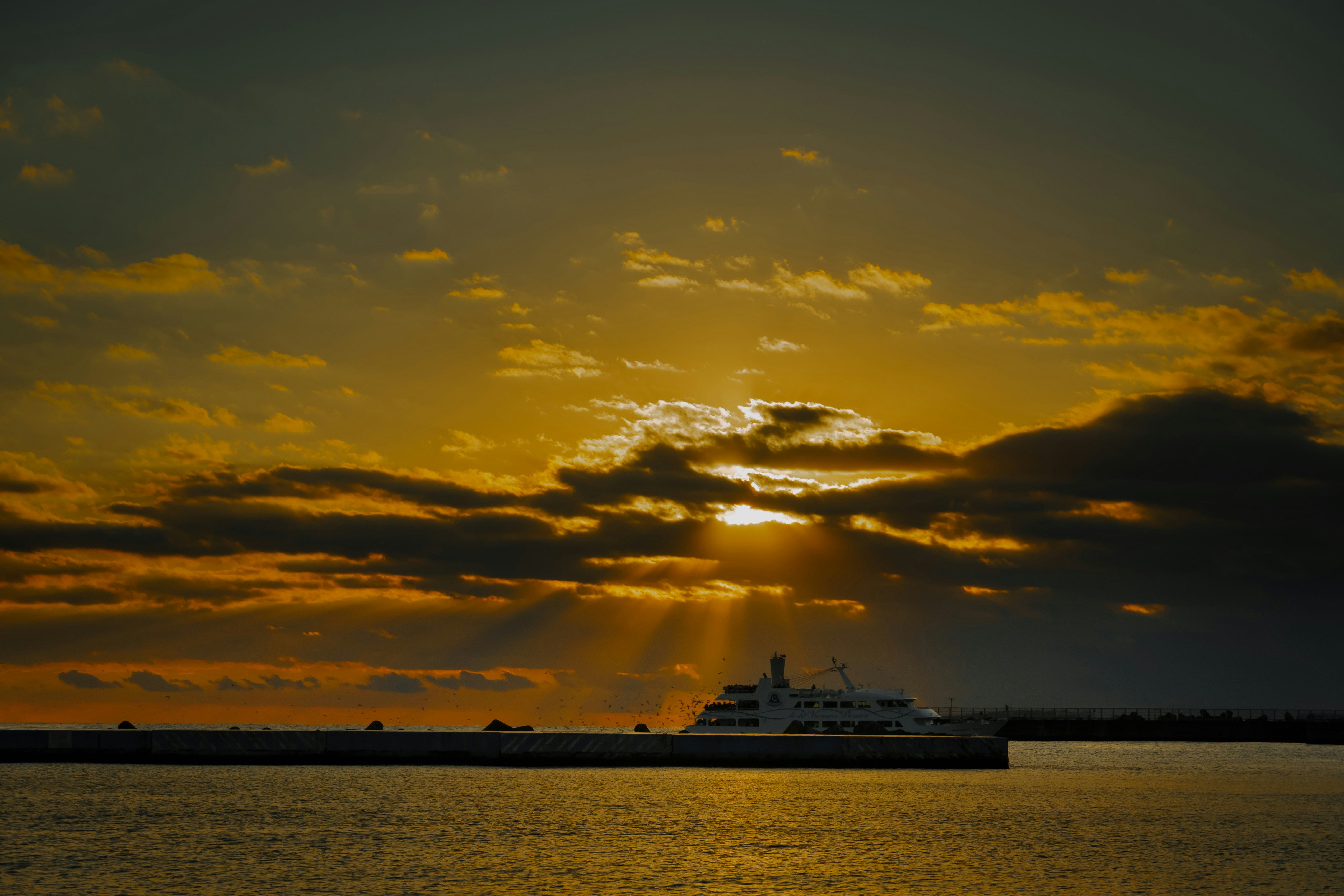 A large white yacht sails on the ocean at sunset.