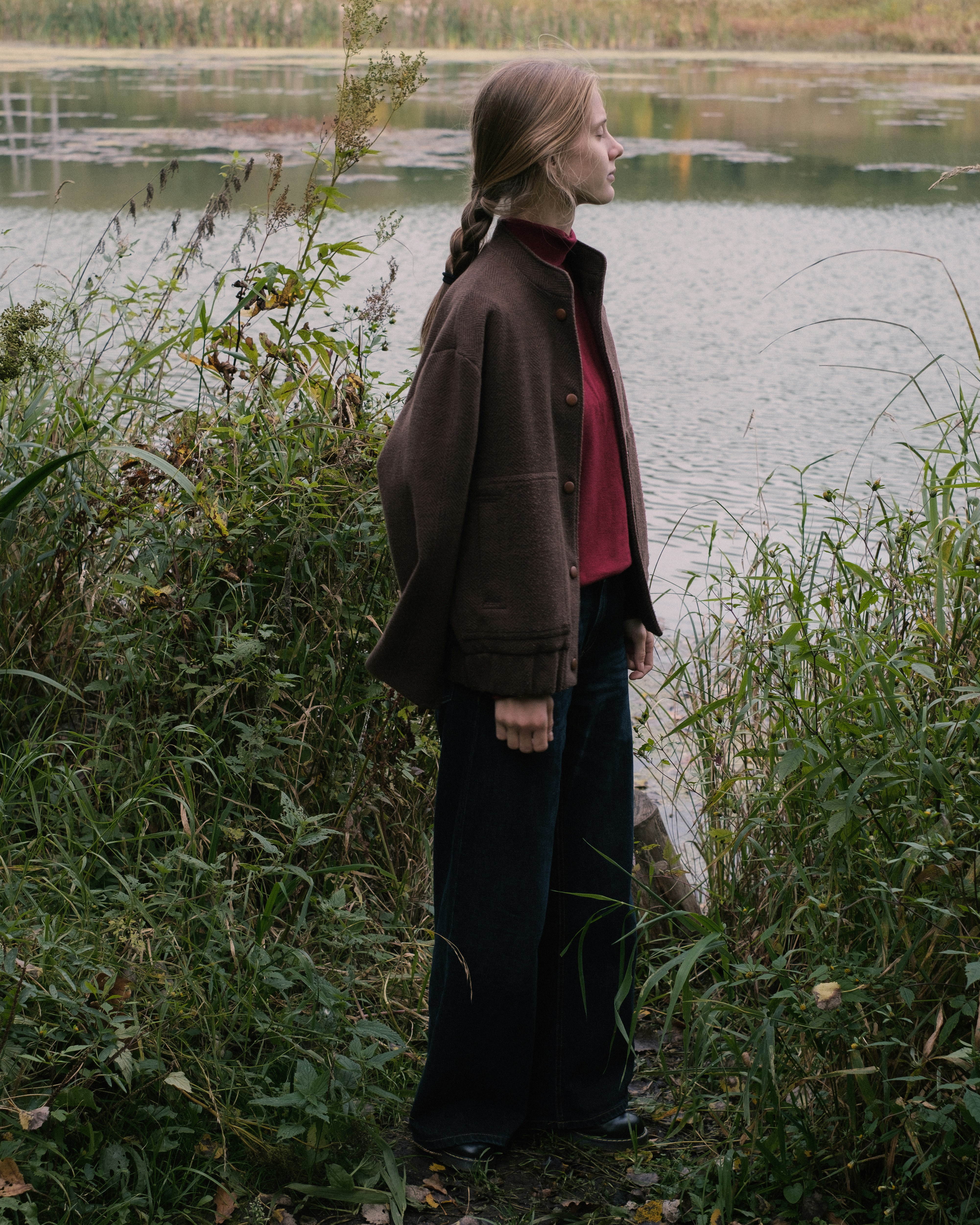 Young woman standing by a calm lake in nature