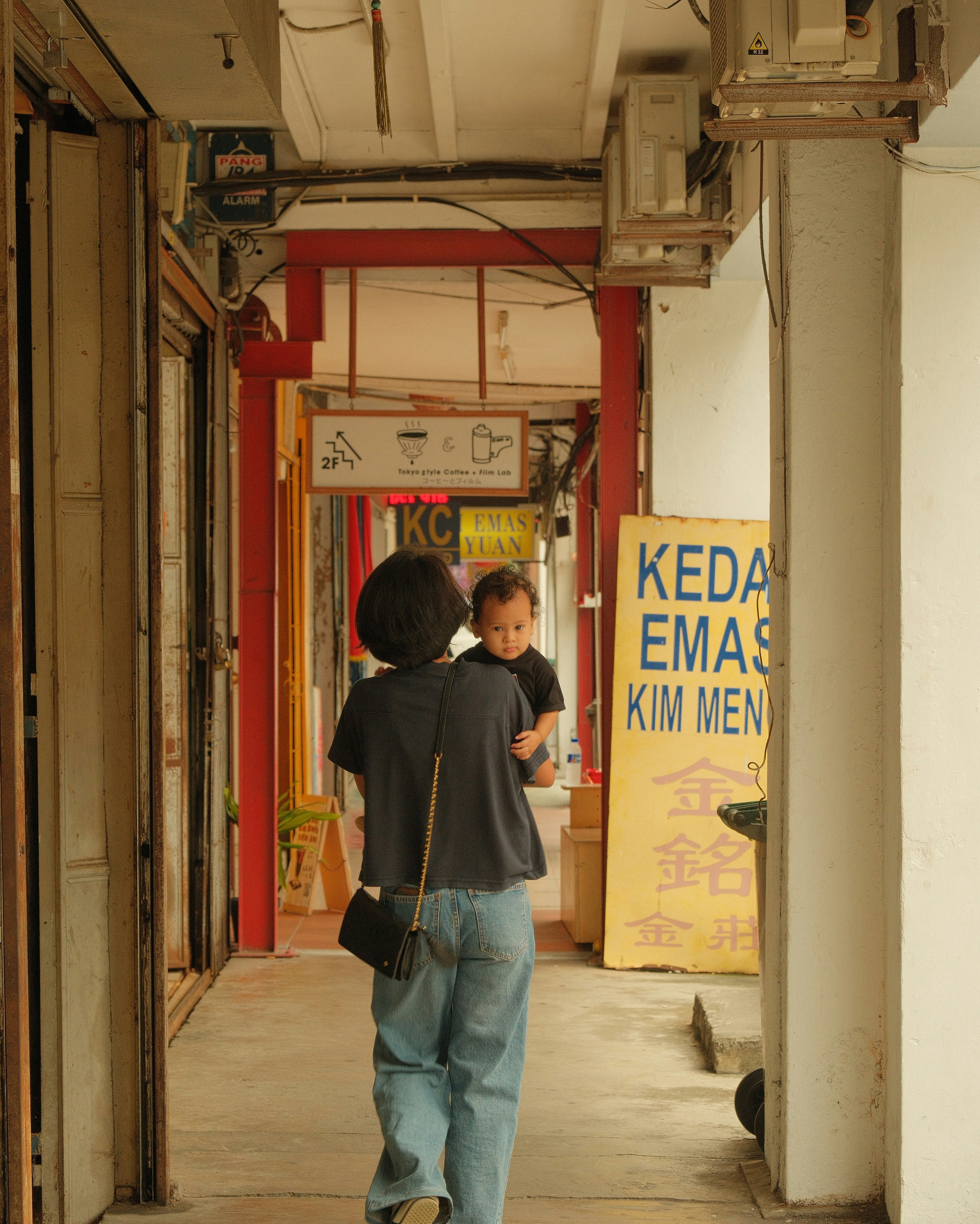 Woman carrying a baby down a covered walkway.