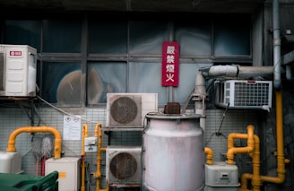 Outdoor air conditioning units and yellow pipes on wall.