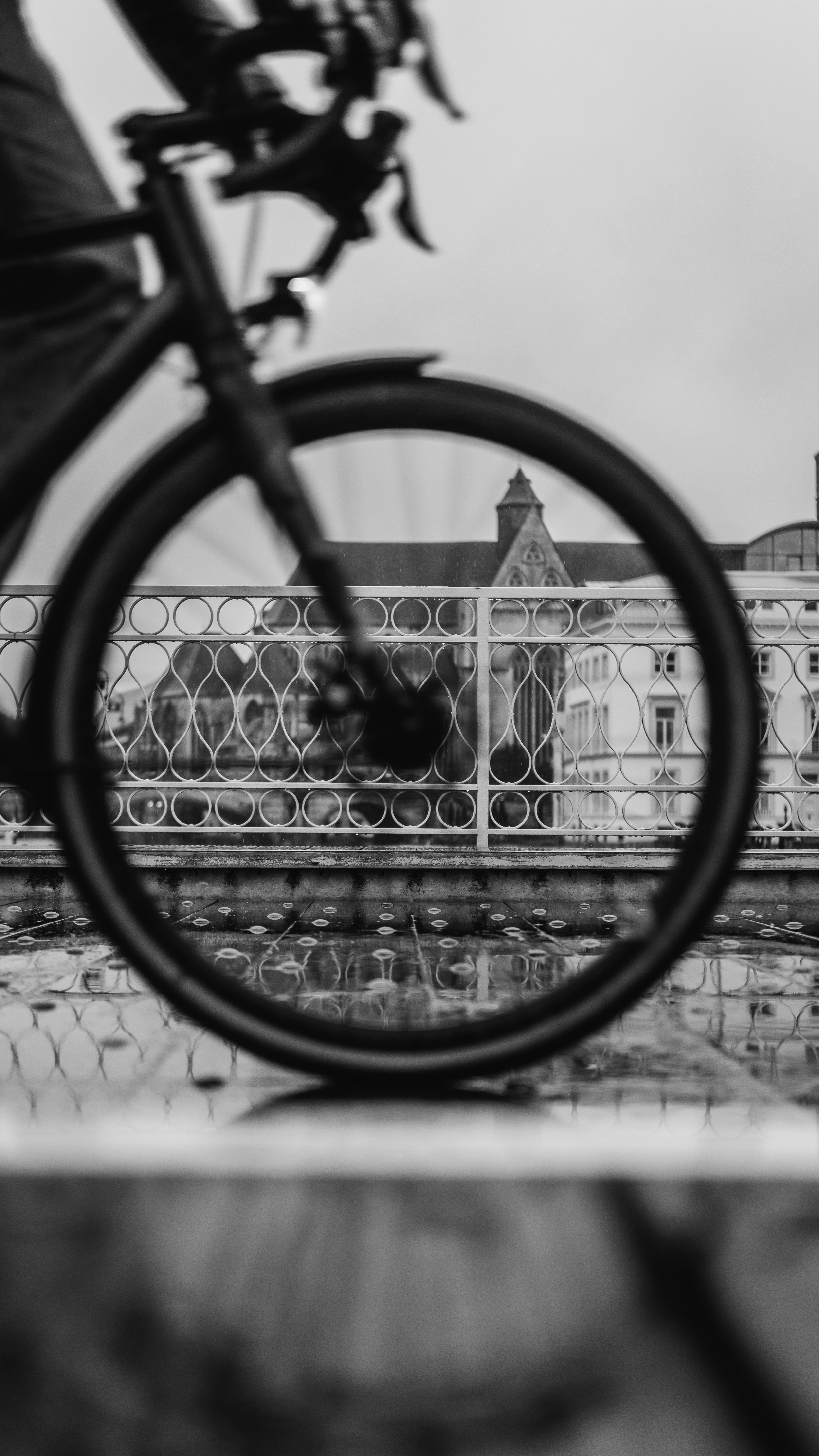 Cyclist on a bridge with reflections on wet ground