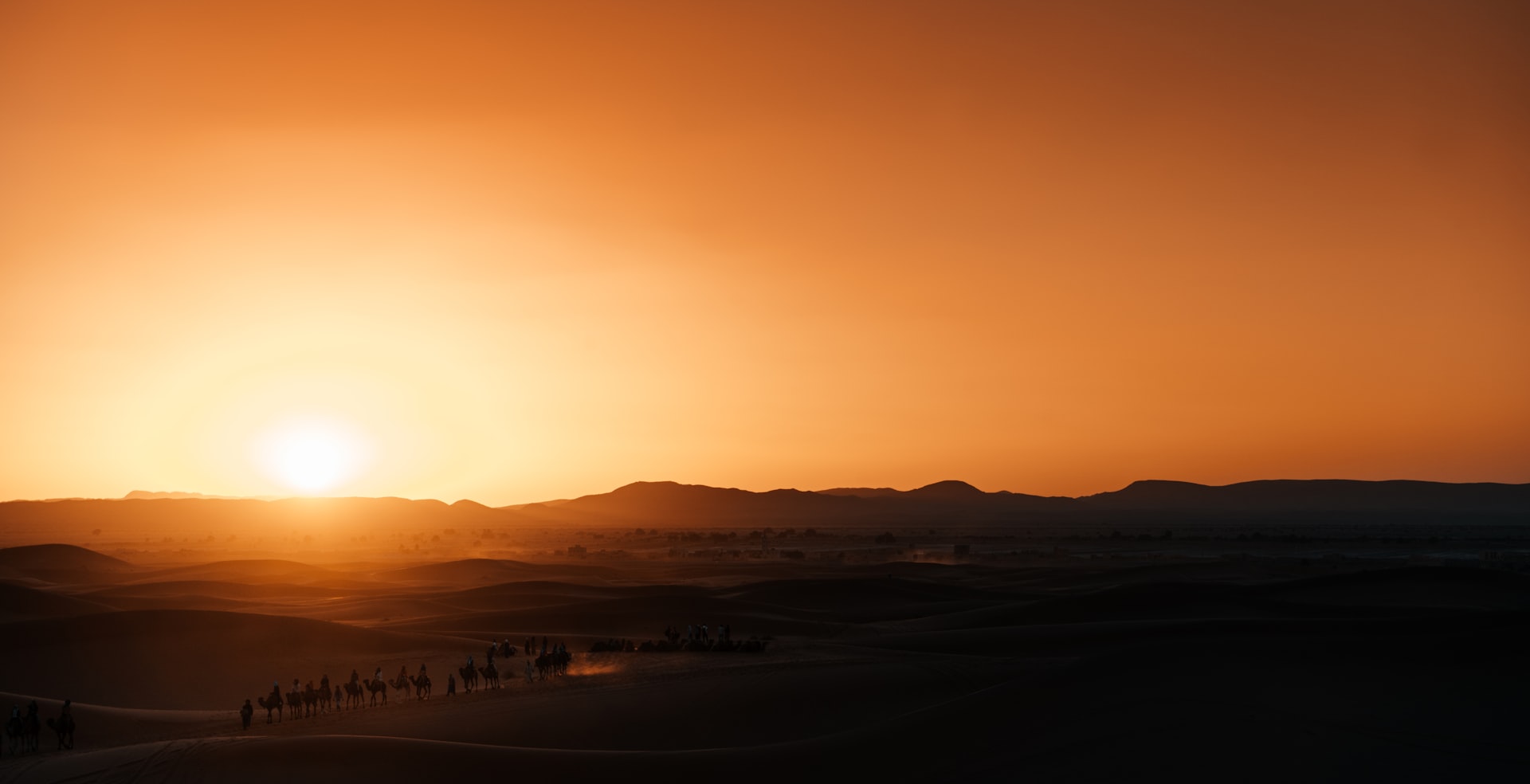 Desert landscape at sunset with distant mountains.
