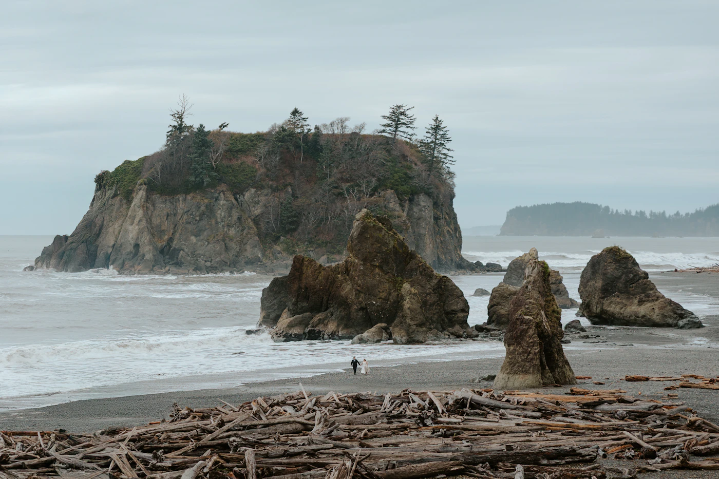 Couple in wedding attire on a dramatic rocky Pacific coastline with sea stacks