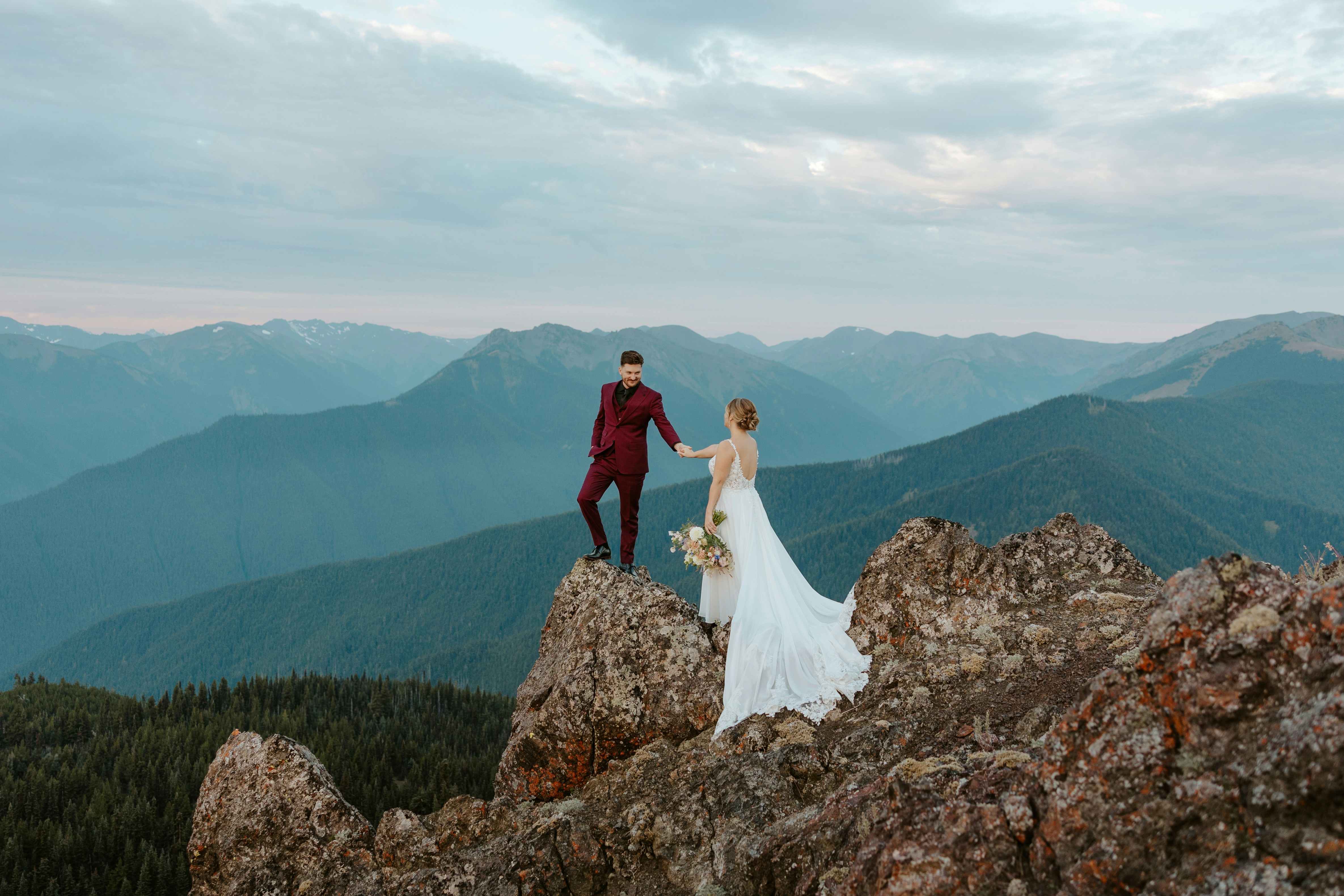 Bride and groom on mountain peak at sunset
