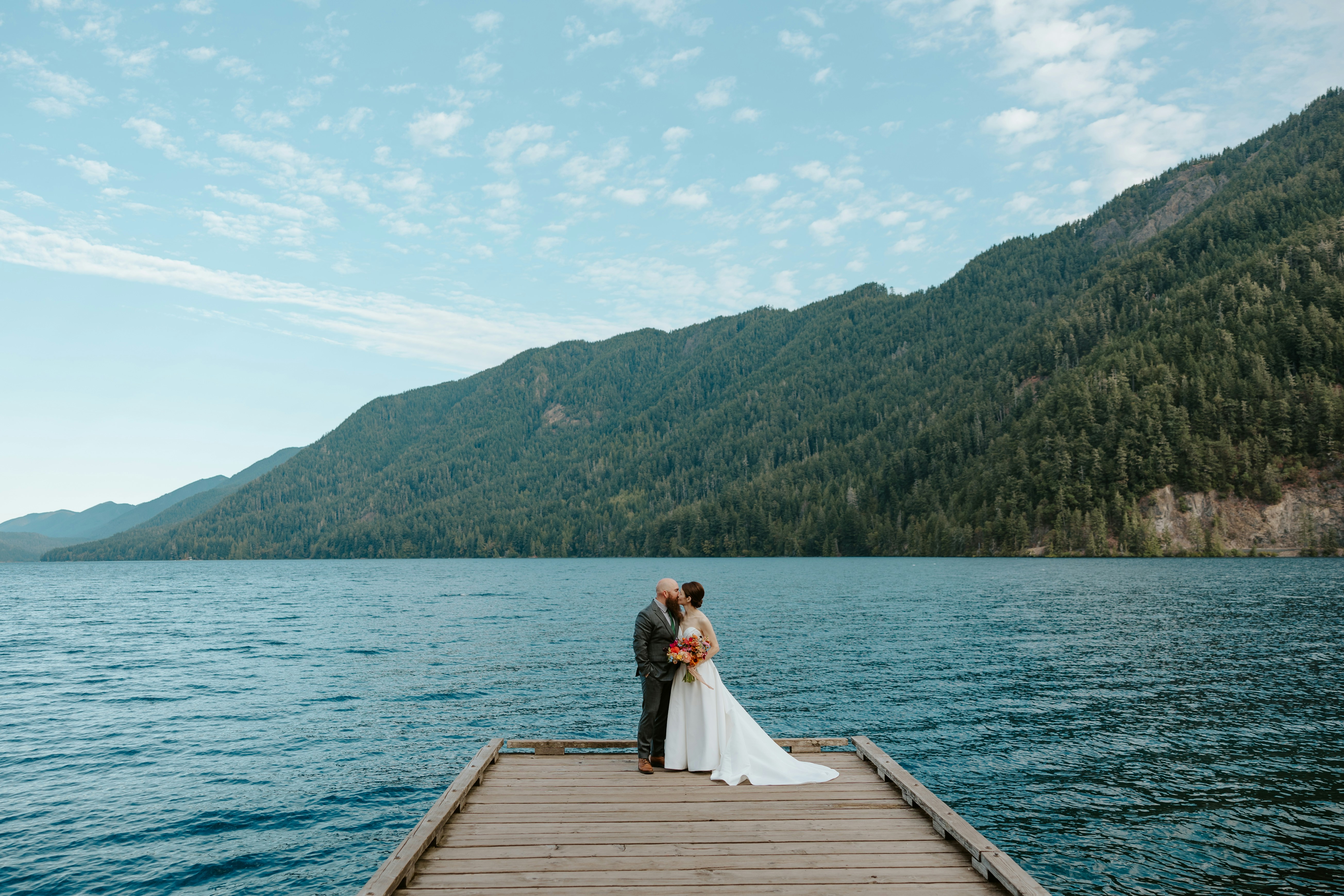 A couple on a dock by a lake with mountains