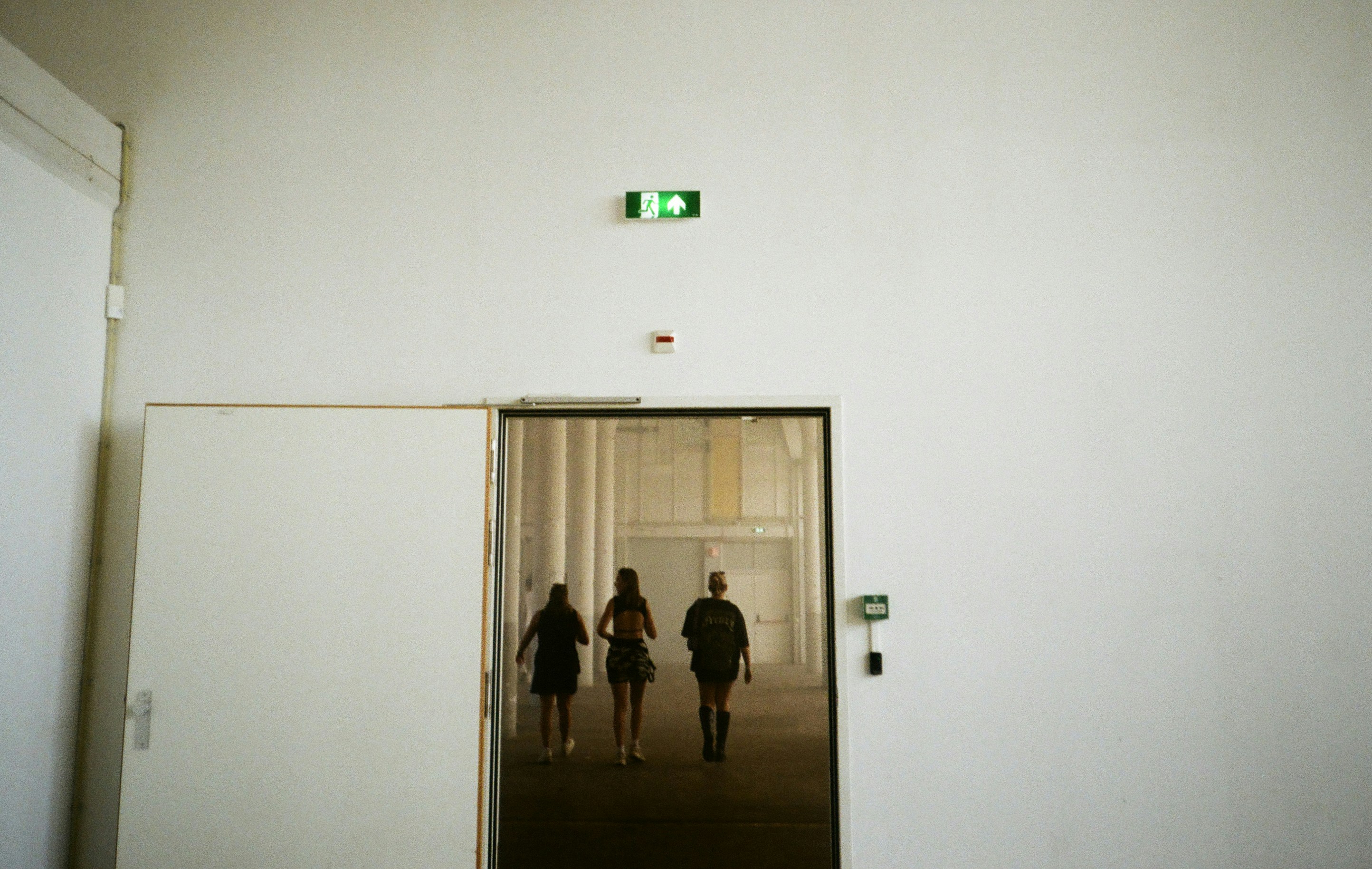 Tre persone entrano da una porta aperta.