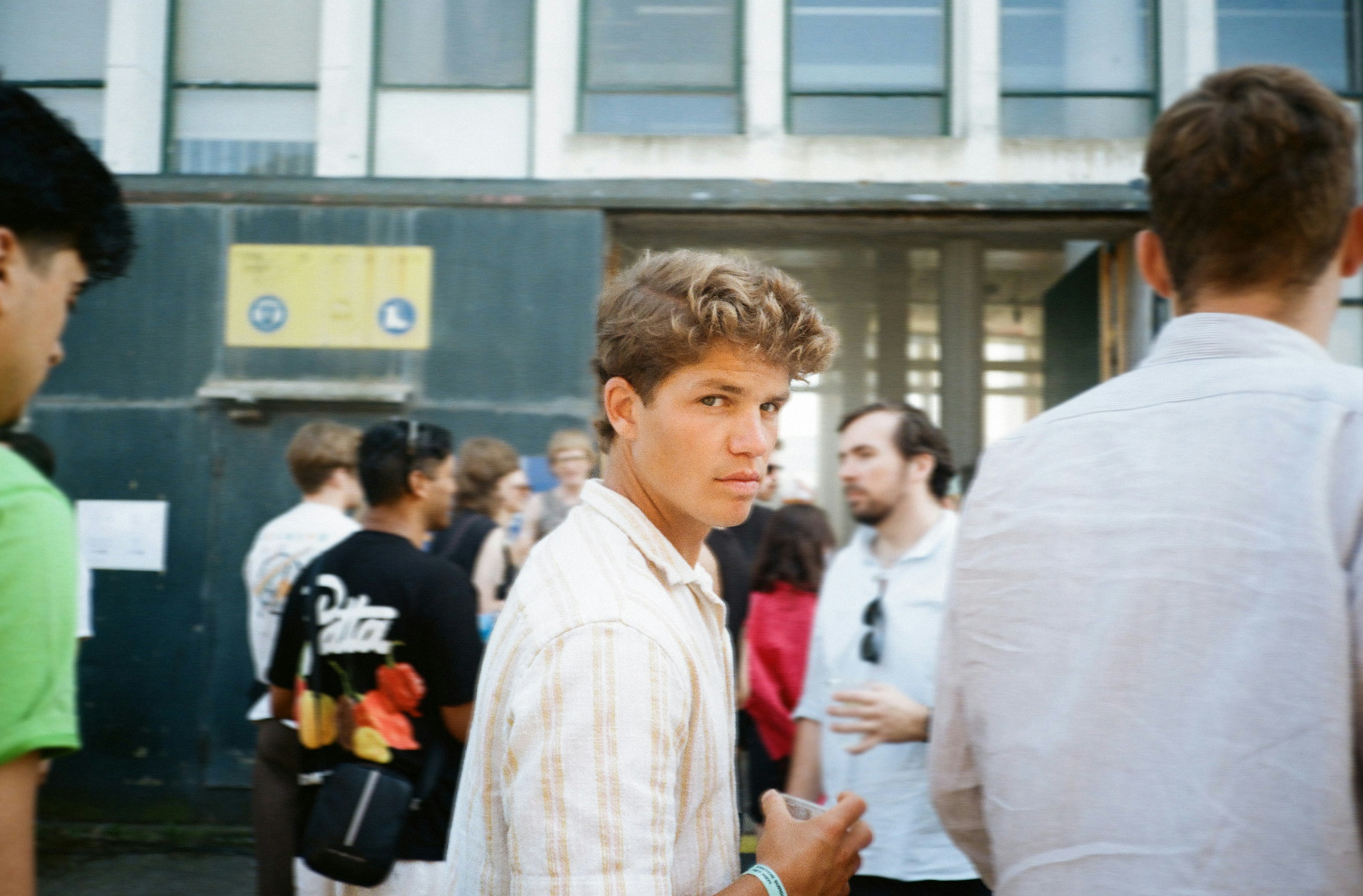 Giovane che guarda la telecamera con persone dietro di lui