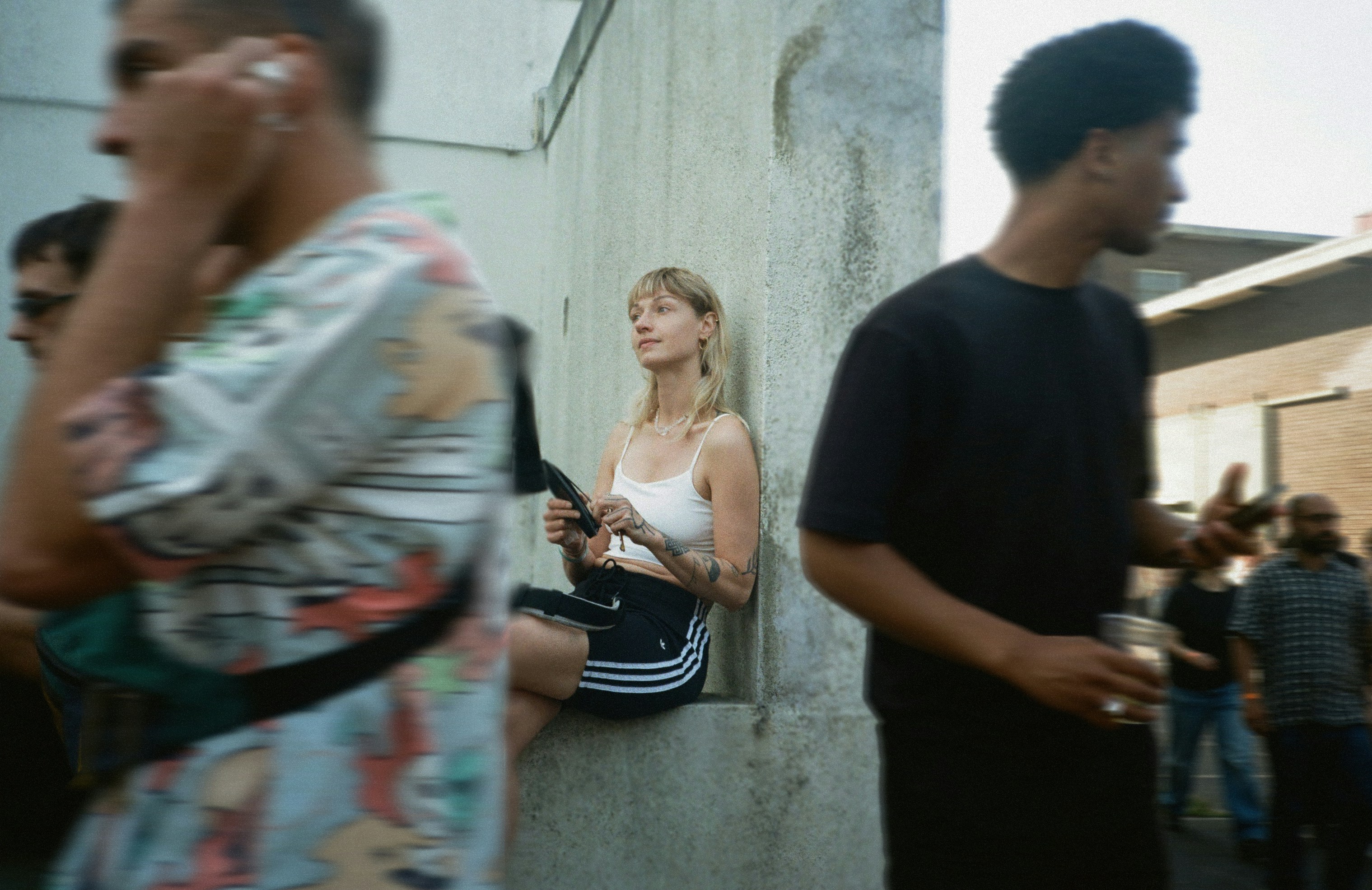 Giovane donna seduta contro il muro con la gente intorno