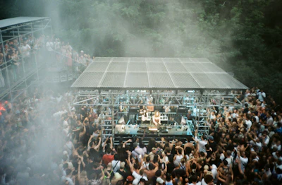 A crowded outdoor music festival with a stage.