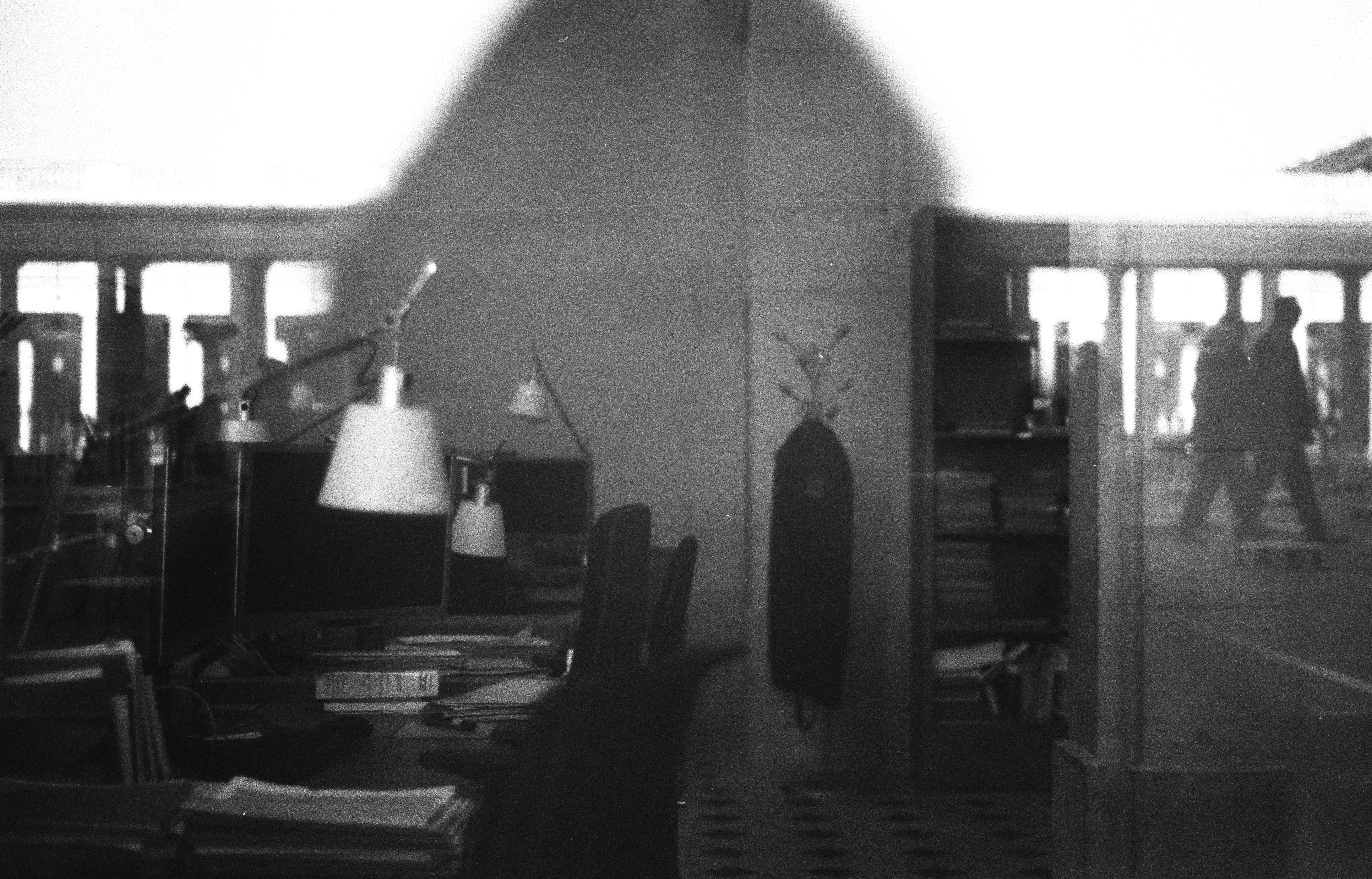 Office interior with desks and two figures walking outside