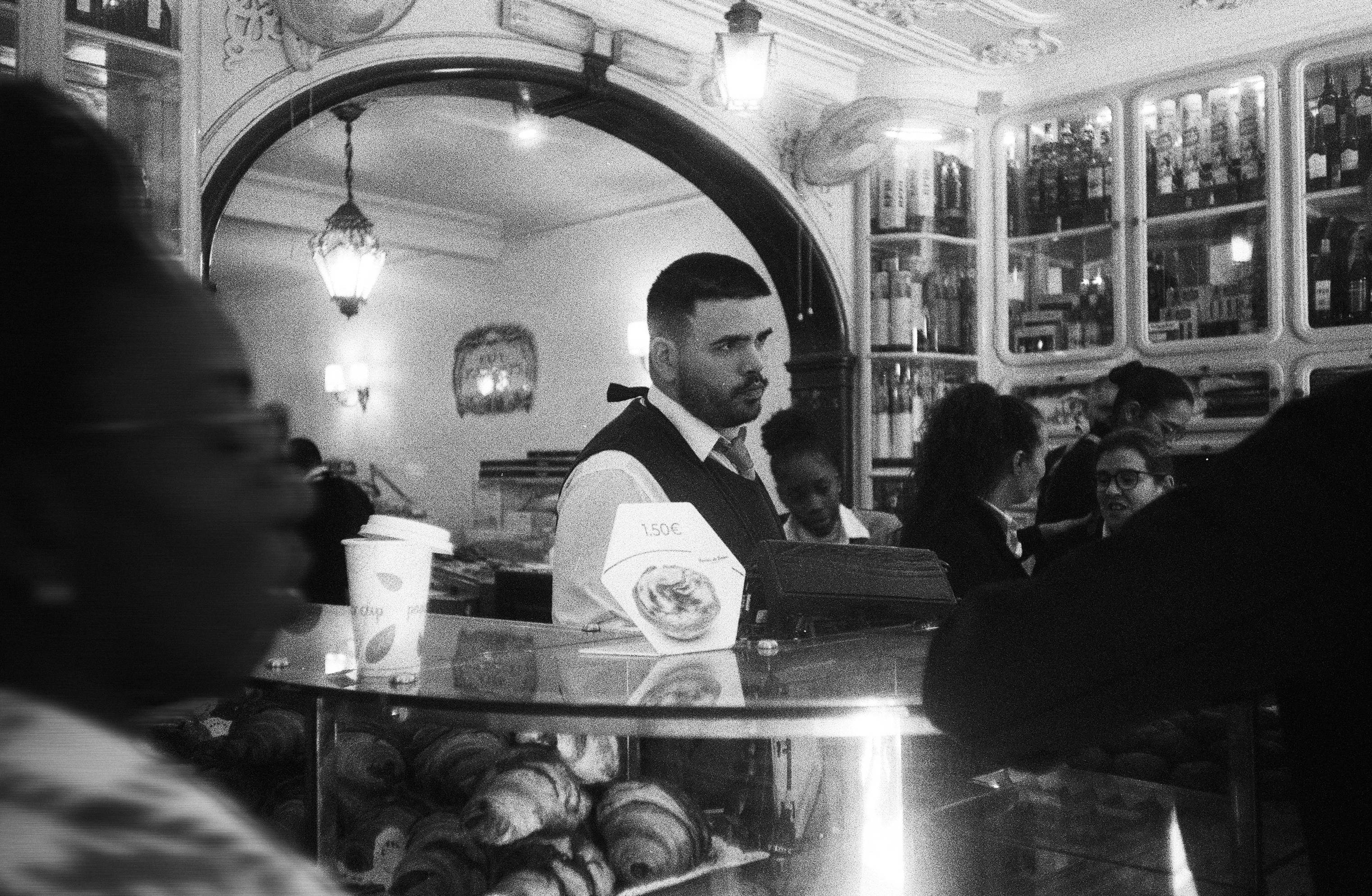 Persone dentro un caffè con dolci in mostra.