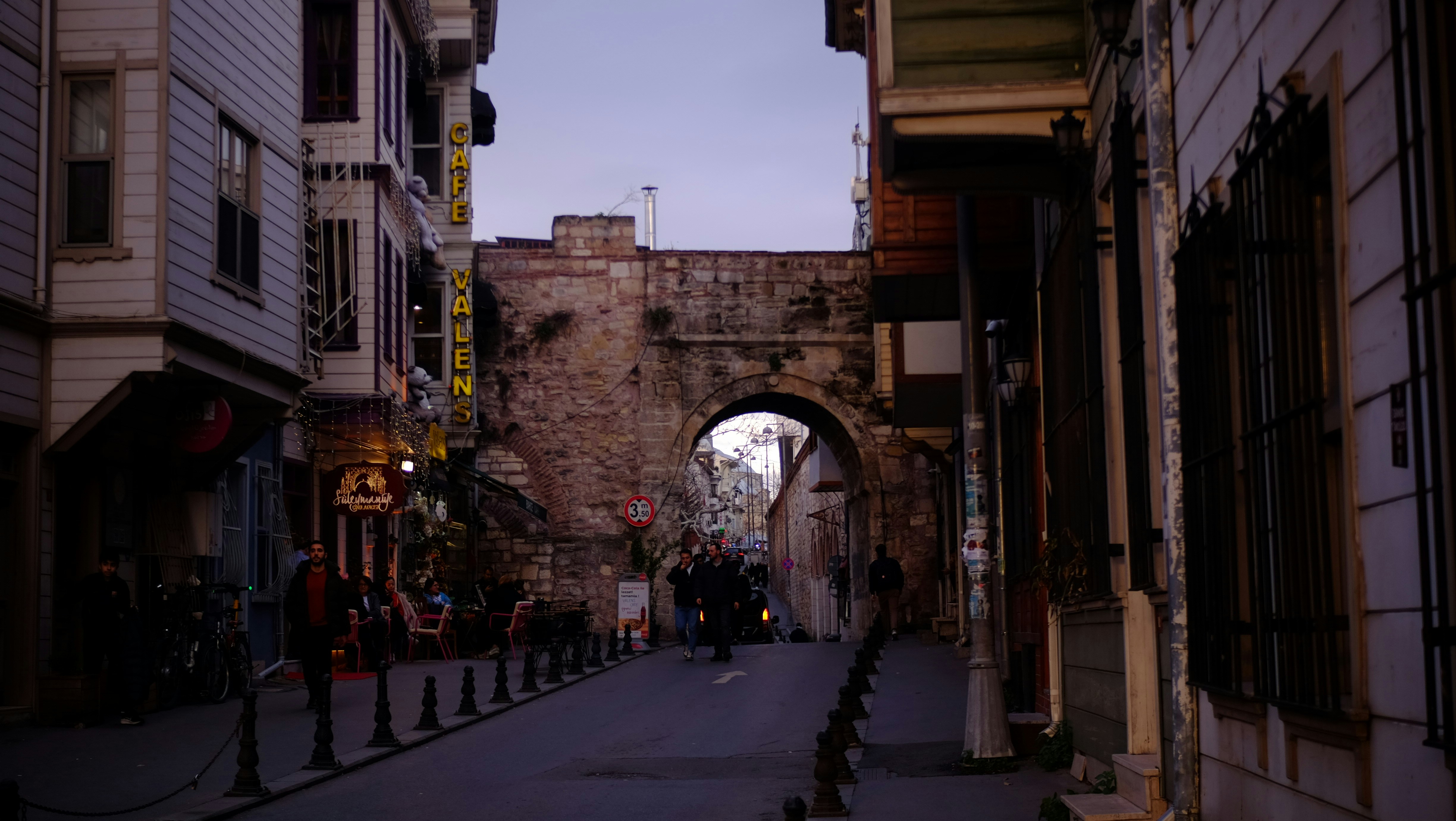 Historic stone archway over a cobblestone street at dusk