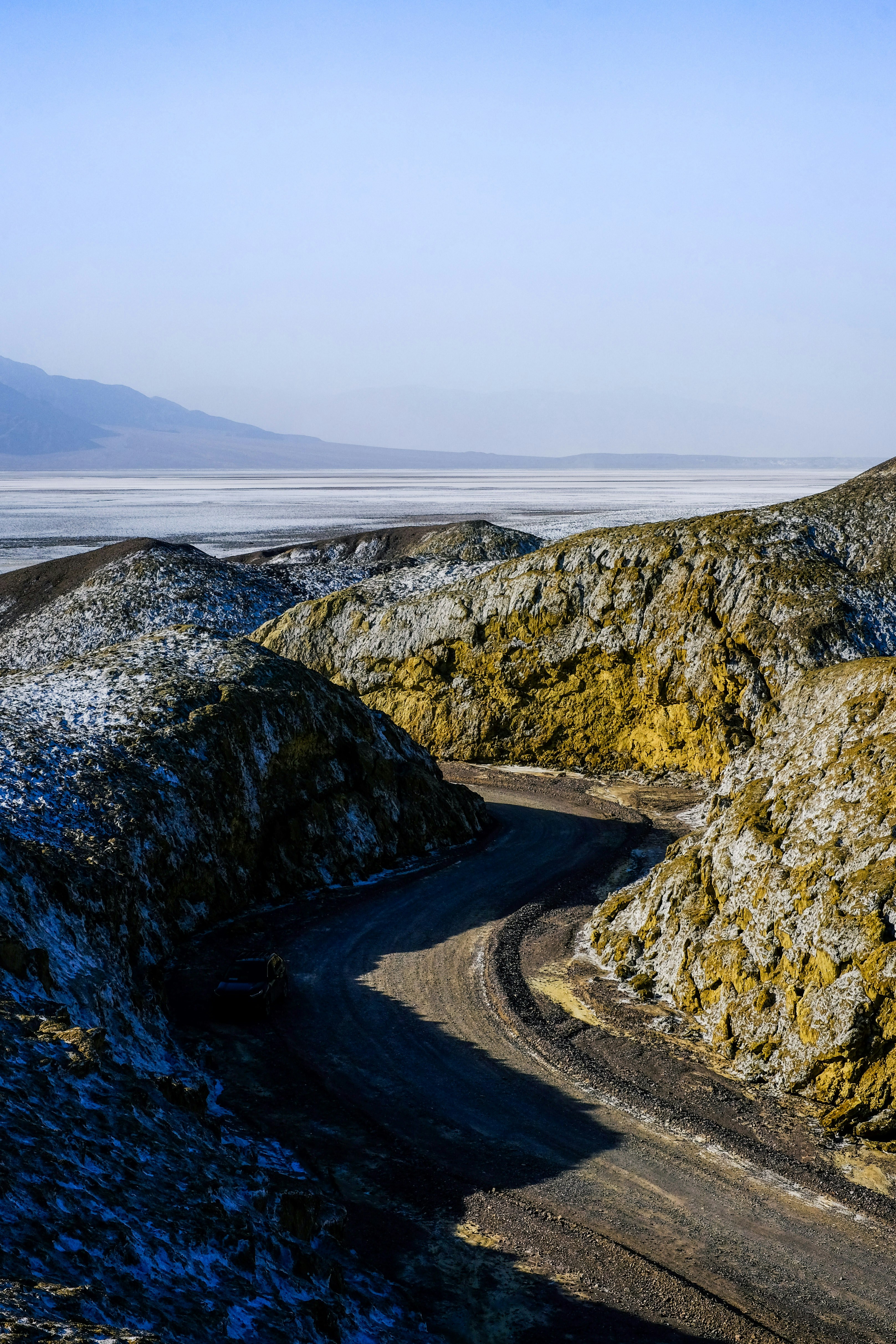 晴れた空の下、岩だらけで荒涼とした風景を曲がりくねった未舗装の道