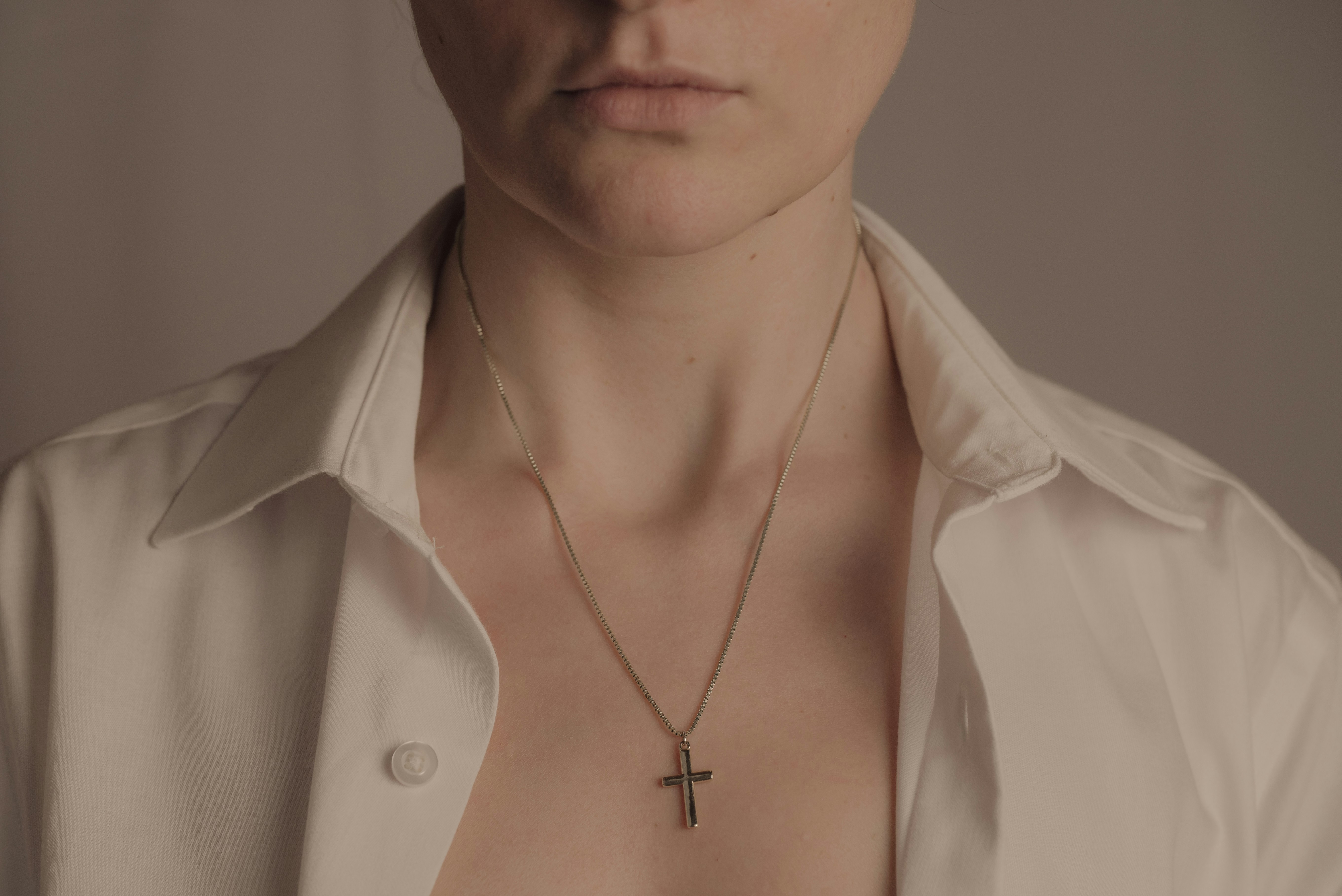 Woman wearing a white shirt and a cross necklace.