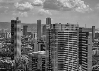 Modern skyscrapers rise against a cloudy sky.