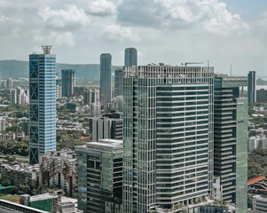 Modern skyscrapers rise above a bustling cityscape under clouds.