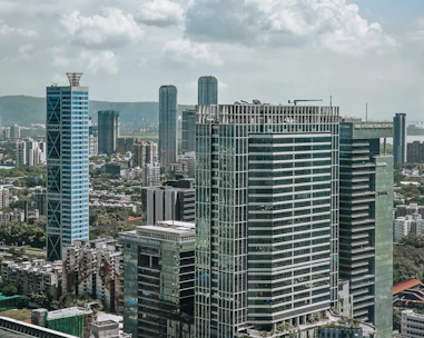 Modern skyscrapers rise above a bustling cityscape under clouds.