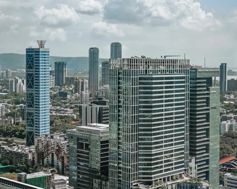 Modern skyscrapers rise above a bustling cityscape under clouds.