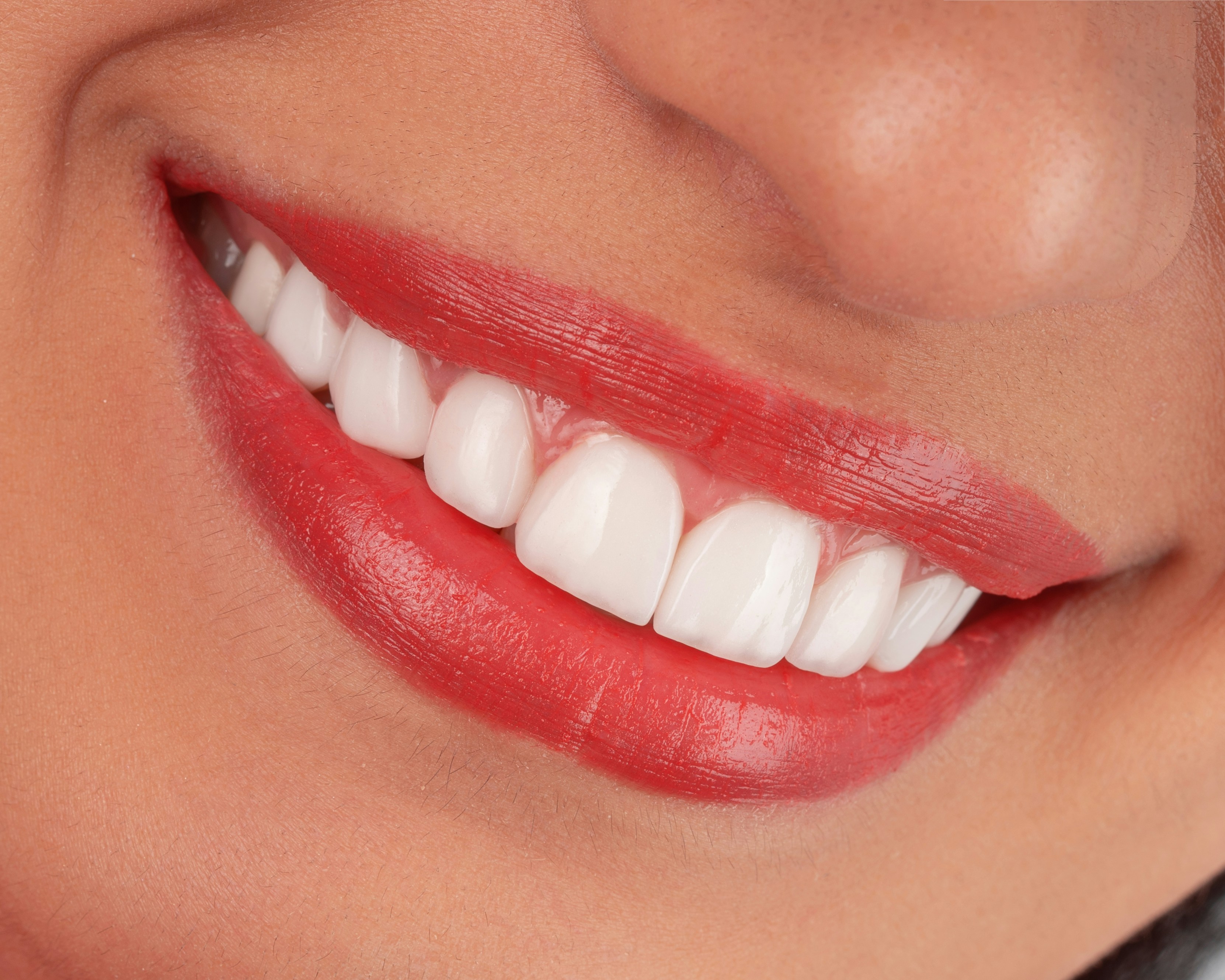 Close-up of a woman's smiling mouth with red lipstick.