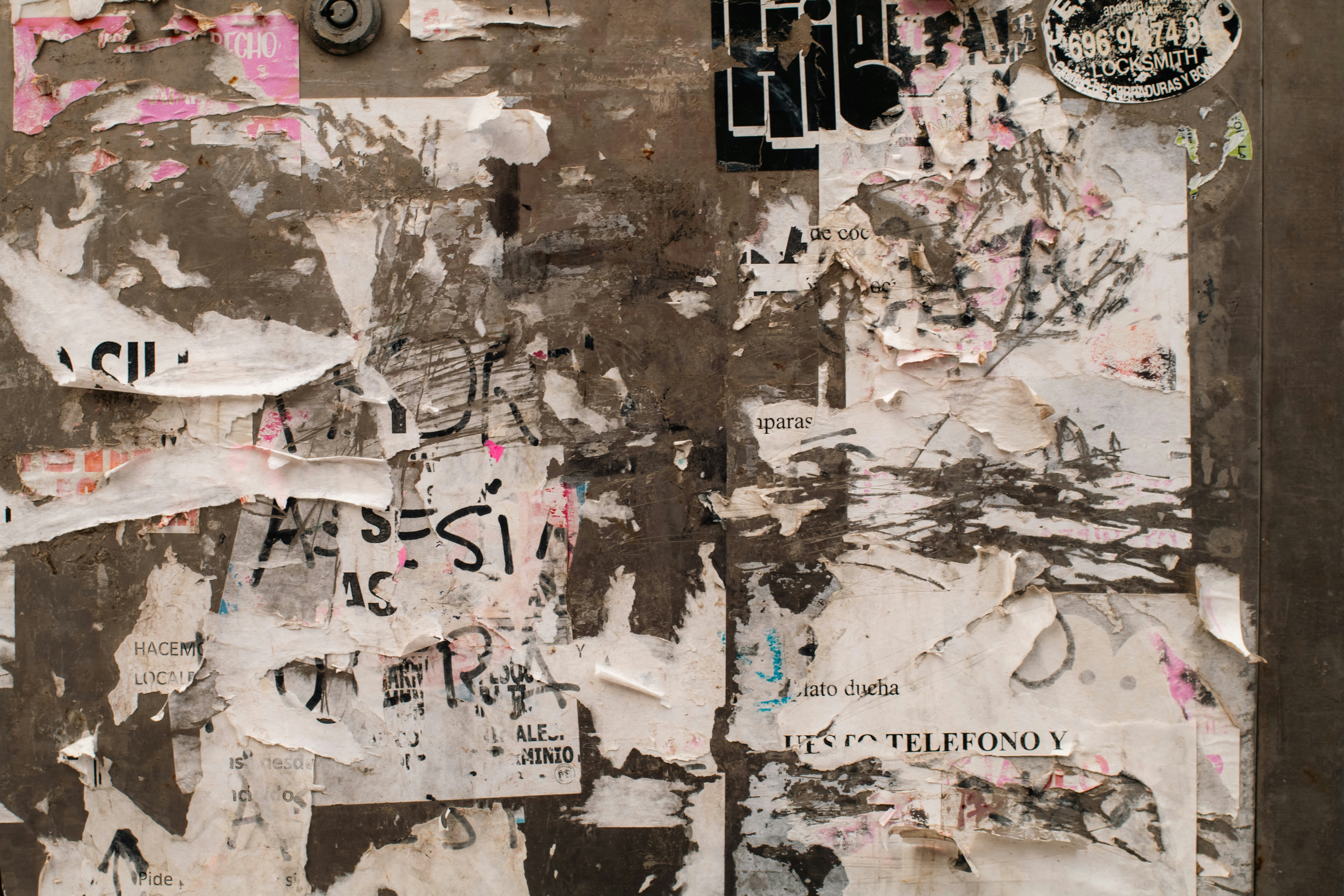 Torn posters and stickers on a weathered wall