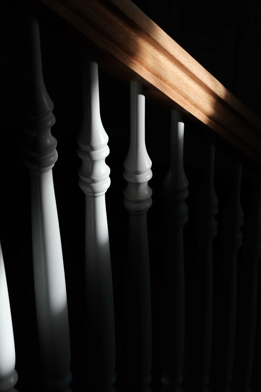Traditional white balusters with a warm wood banister in natural light