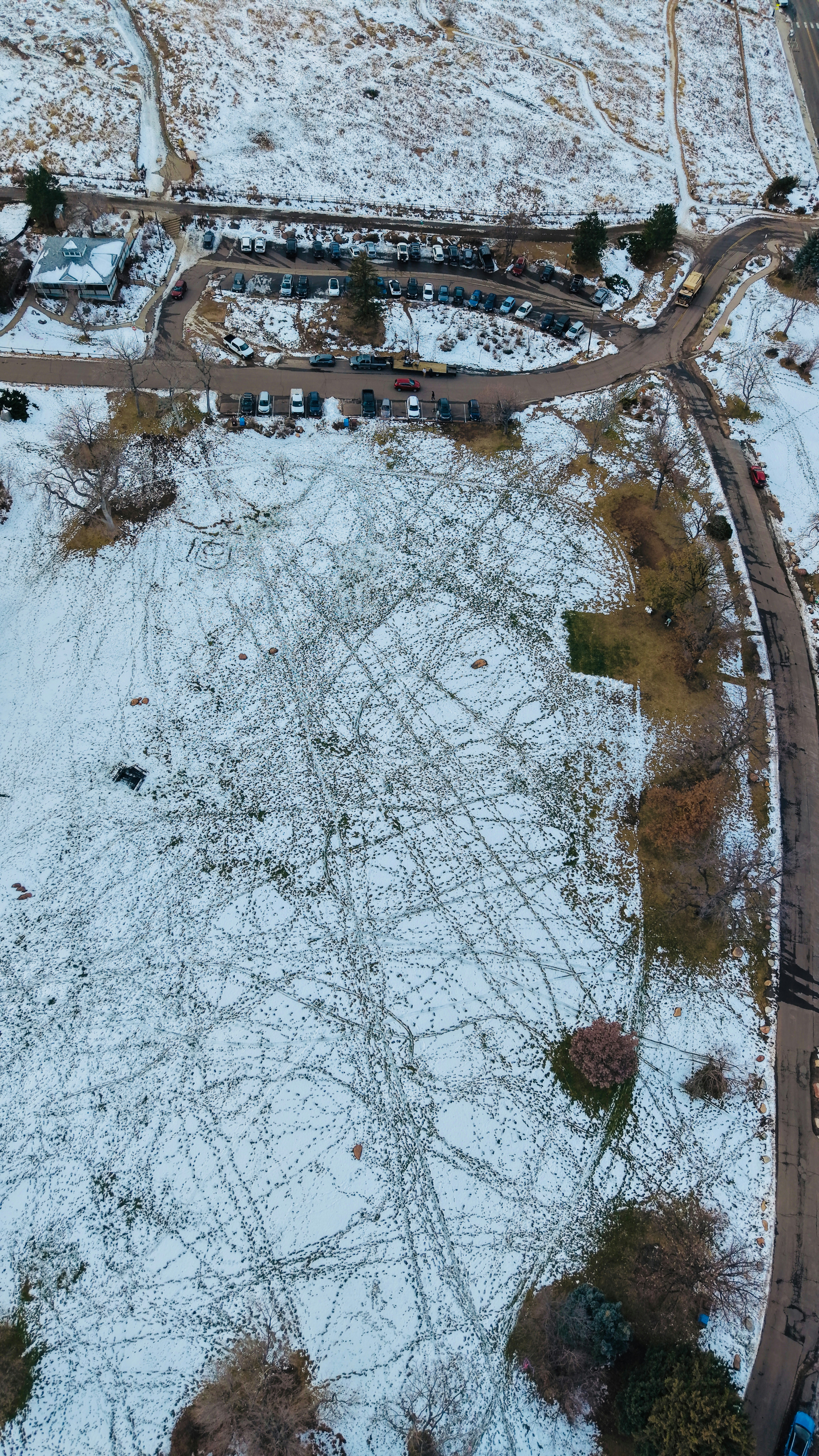 Aerial view of a snow-covered field with tire tracks.