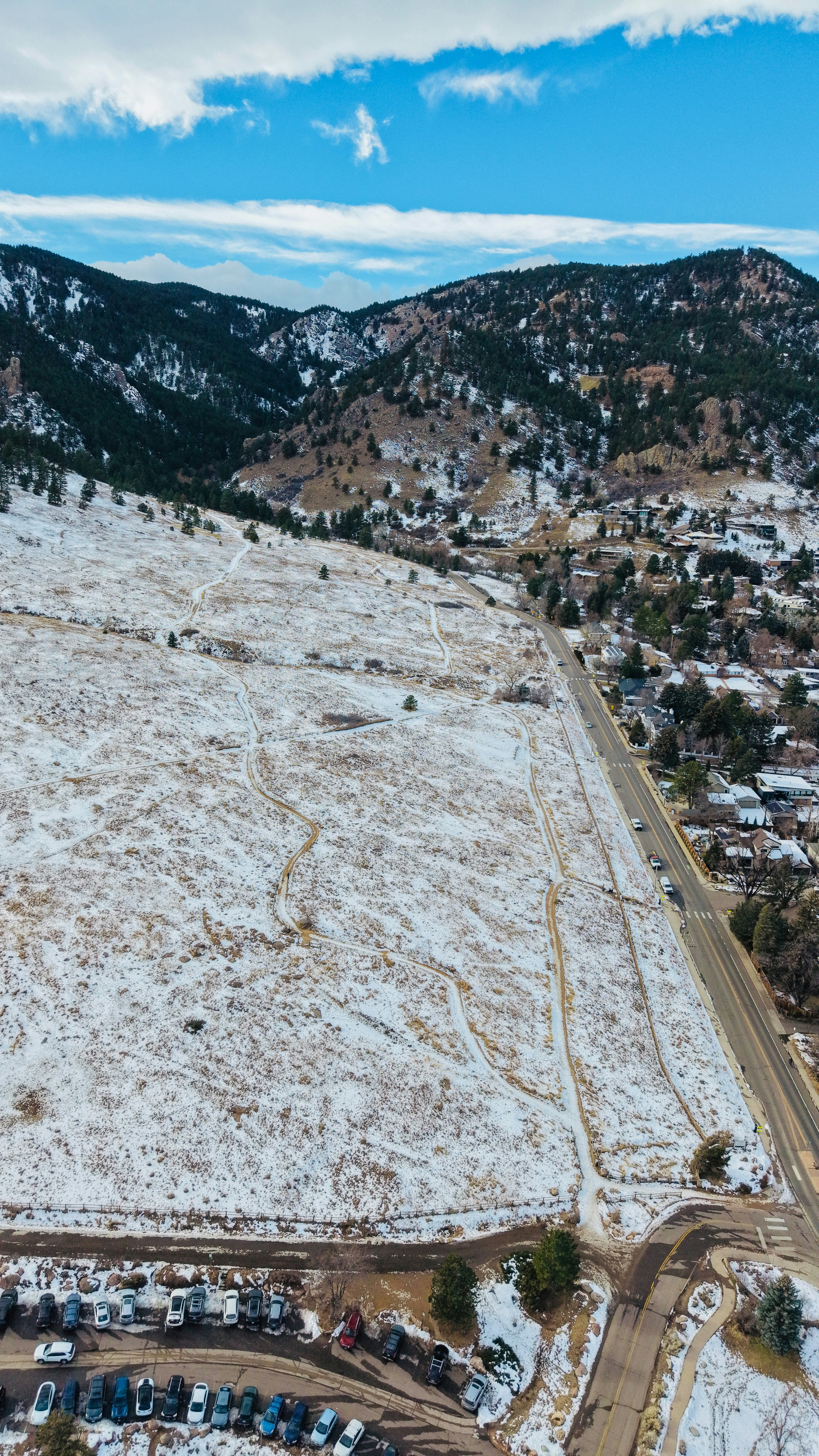 Snow-covered hills with a road and houses below mountains above