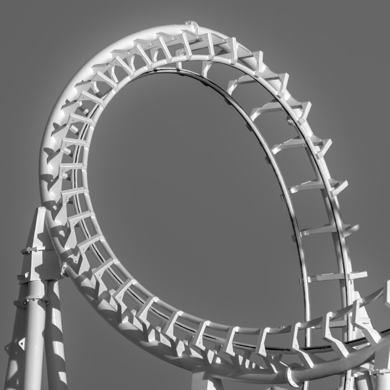 Weiße Achterbahn mit Looping vor blauem Himmel