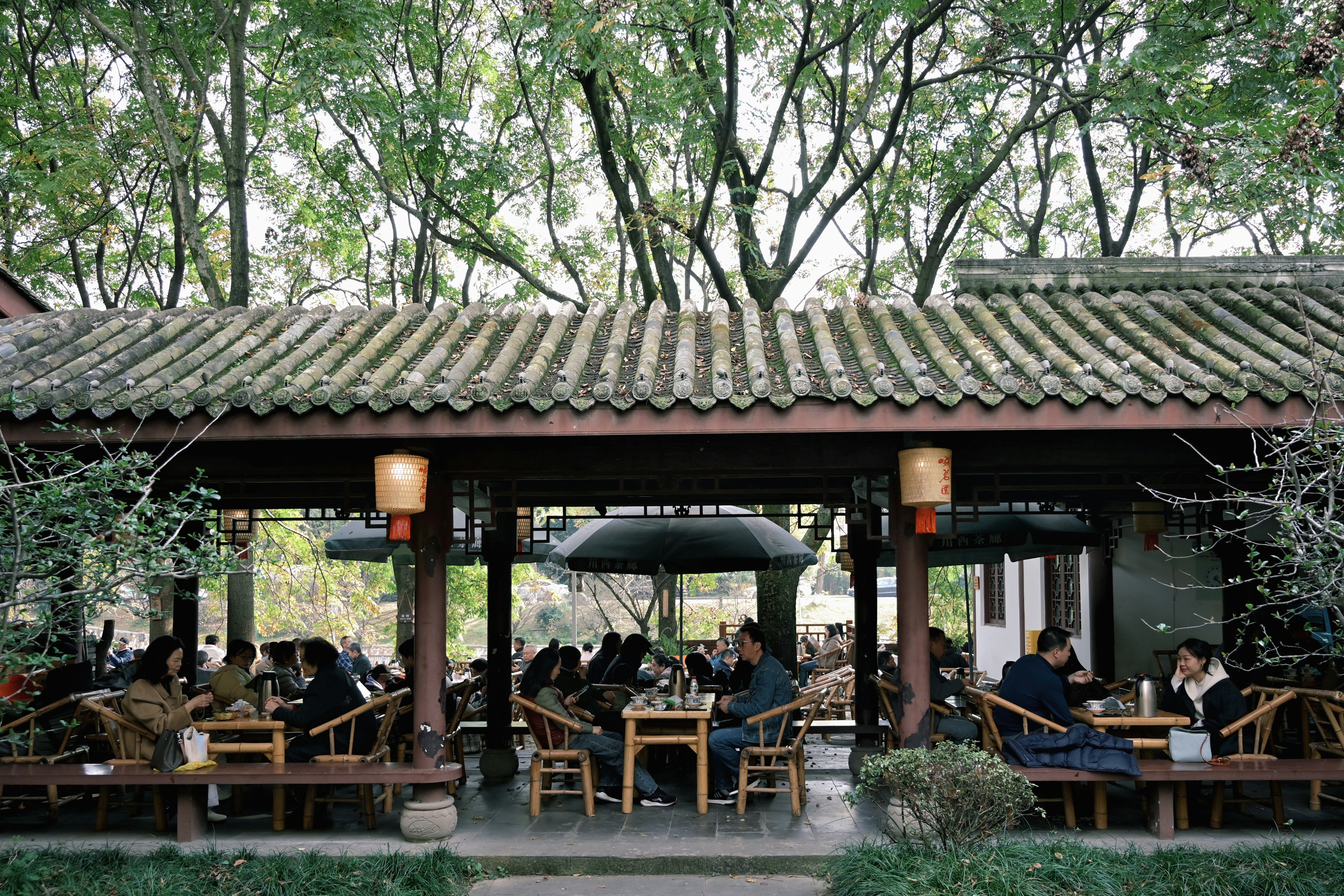People seated at tables under a covered outdoor seating area.