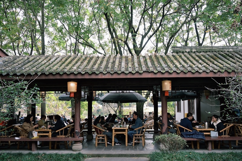 People seated at tables under a covered outdoor seating area.