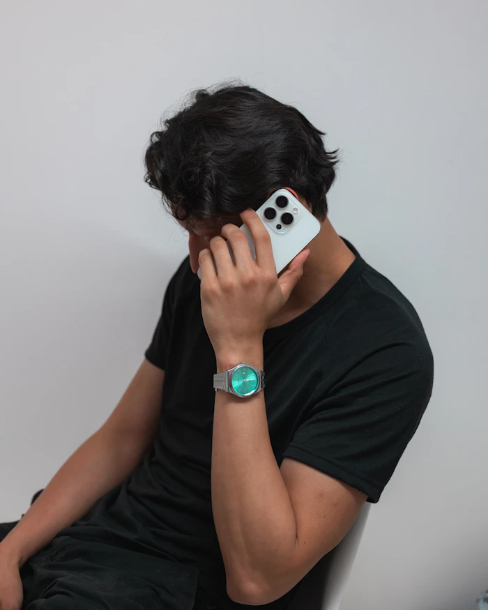 Persona real hablando por celular mientras revisa la hora en su reloj