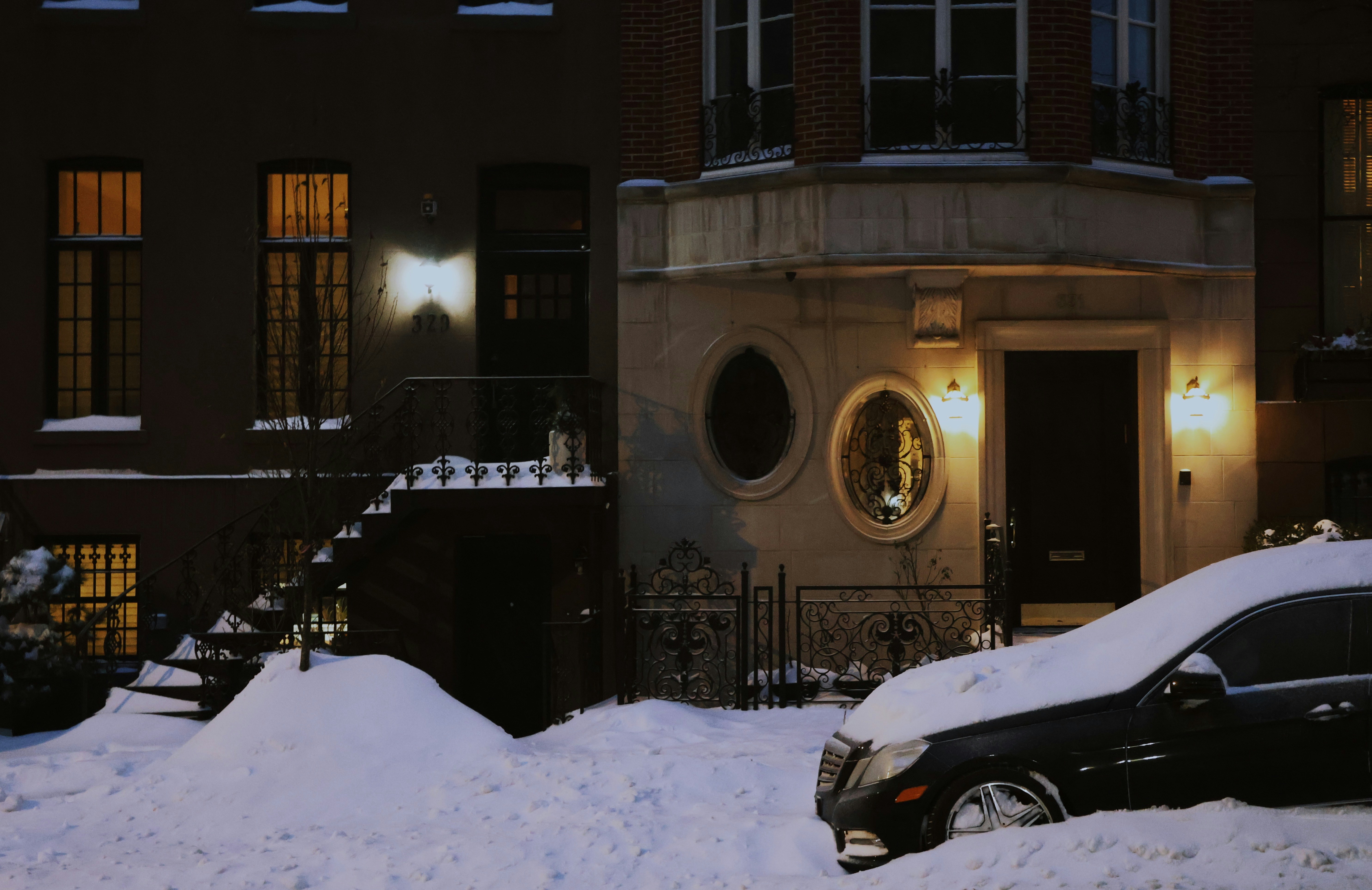 Snow covered car parked outside a building at night