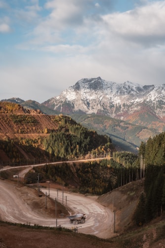 A haul truck navigating a winding mountain road, illustrating the remote and rugged locations where gold mining operations take place