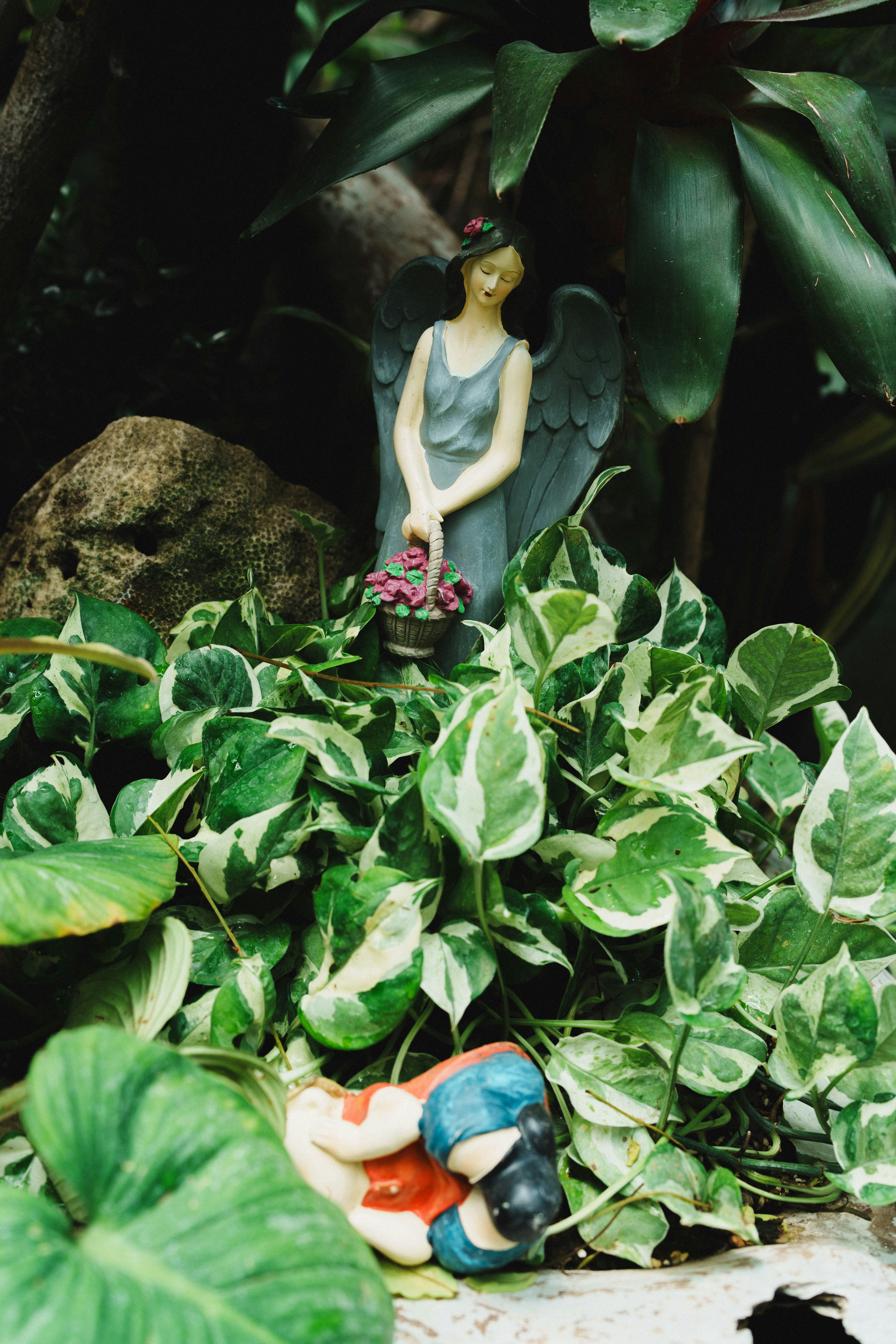 Angel statue holding flower basket near sleeping figure
