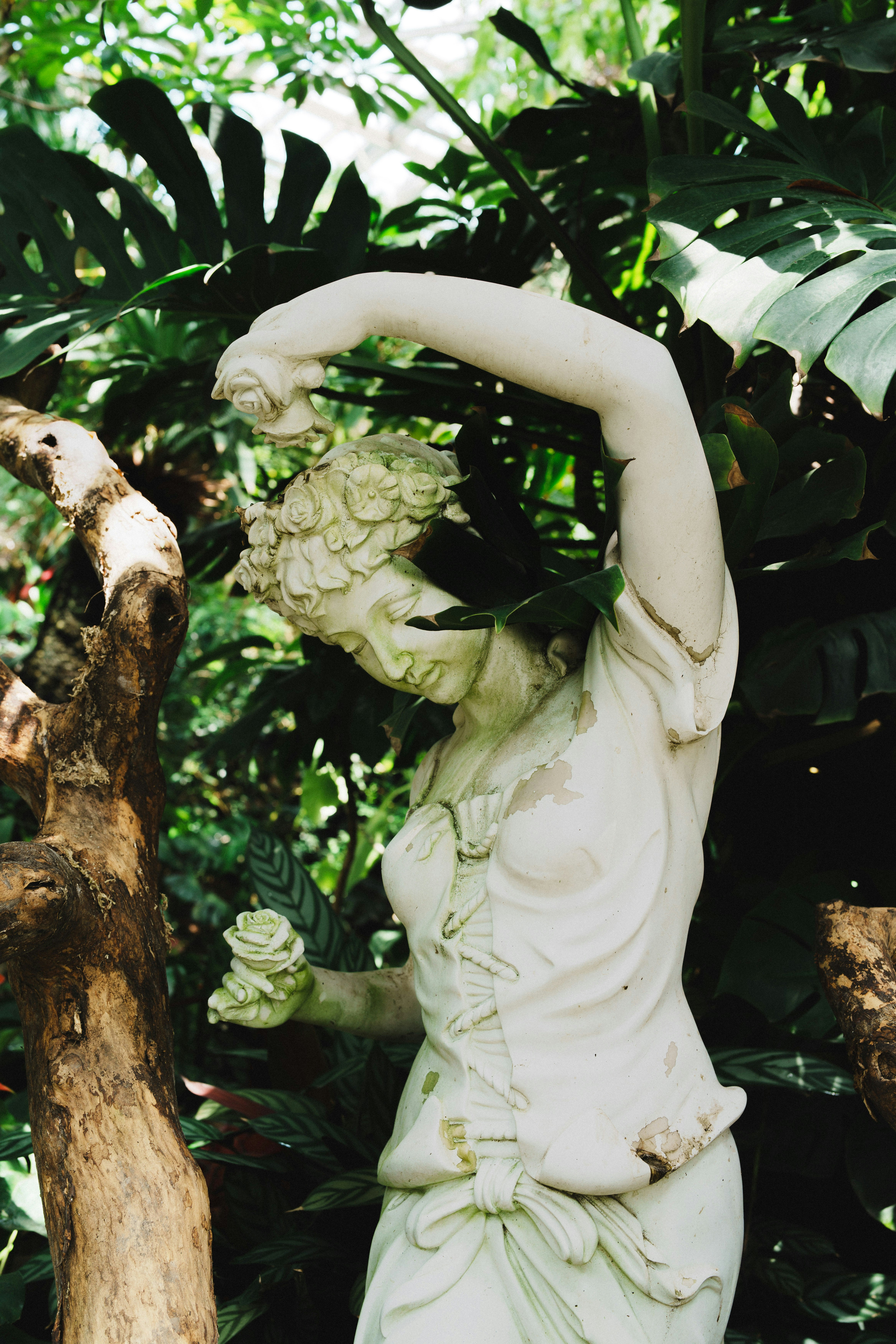 A classical statue of a woman holding roses.