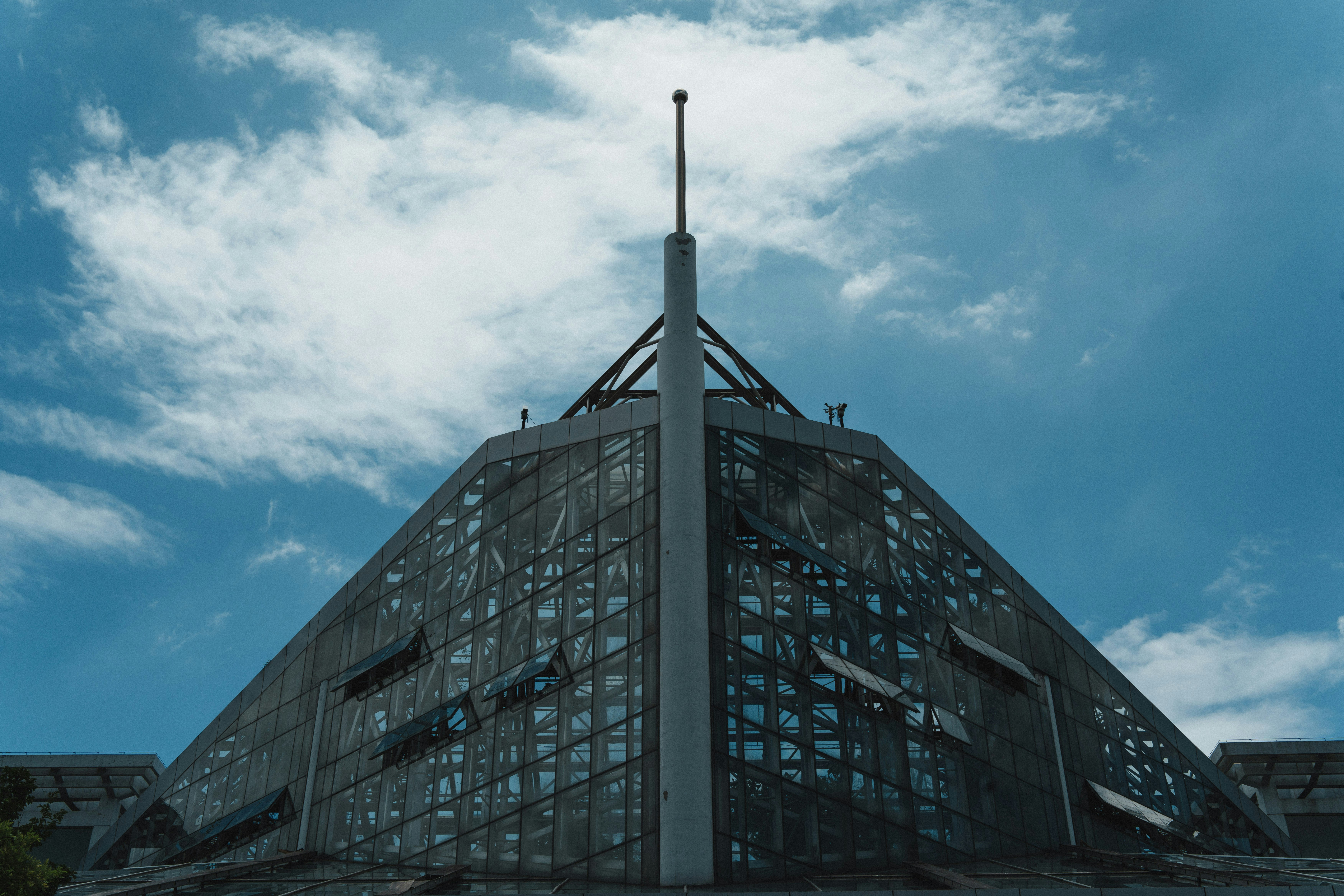 Modern geometric building with glass facade under blue sky.