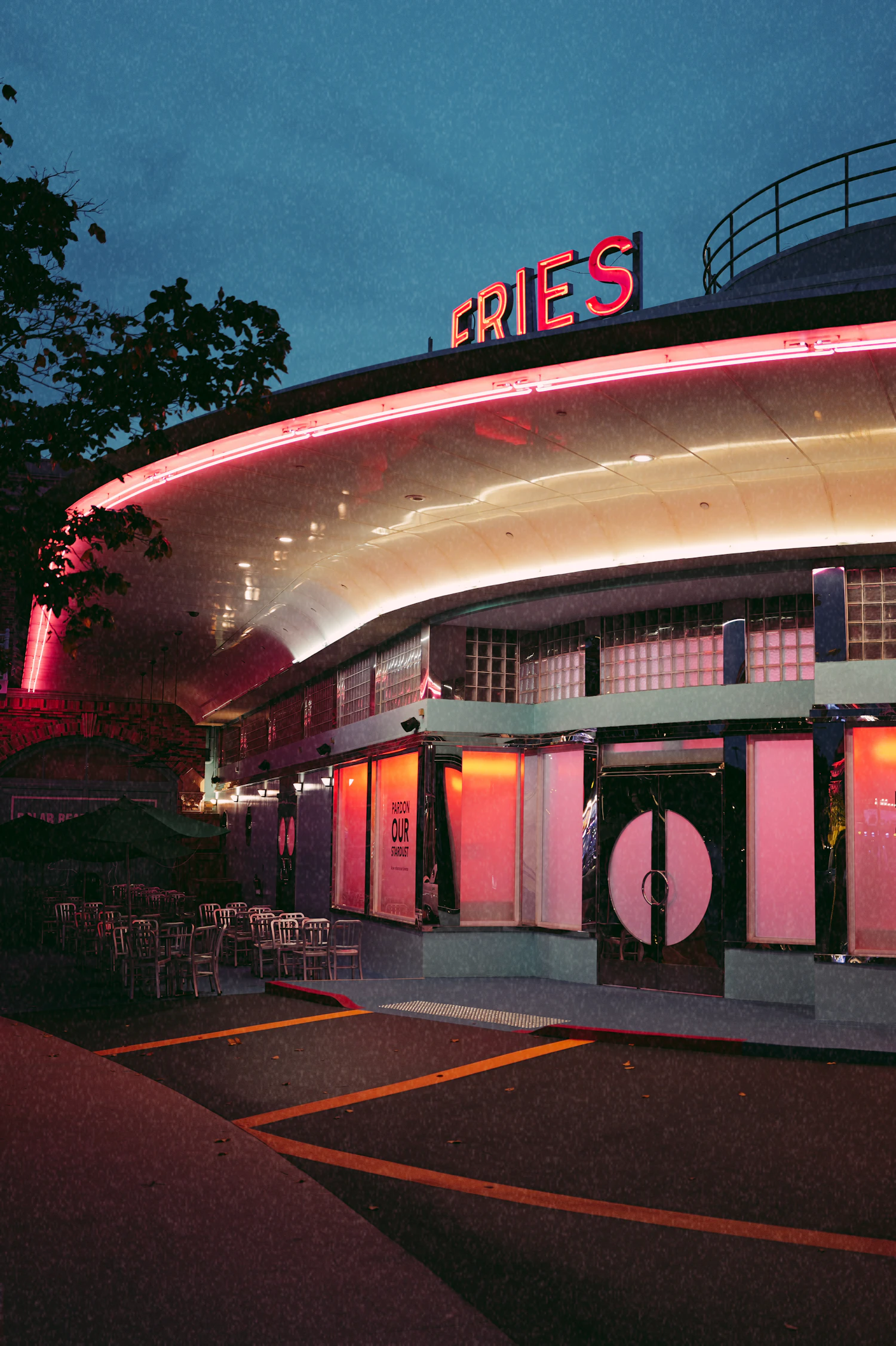 A curved diner front glowing pink and red at dusk, neon running along the roofline