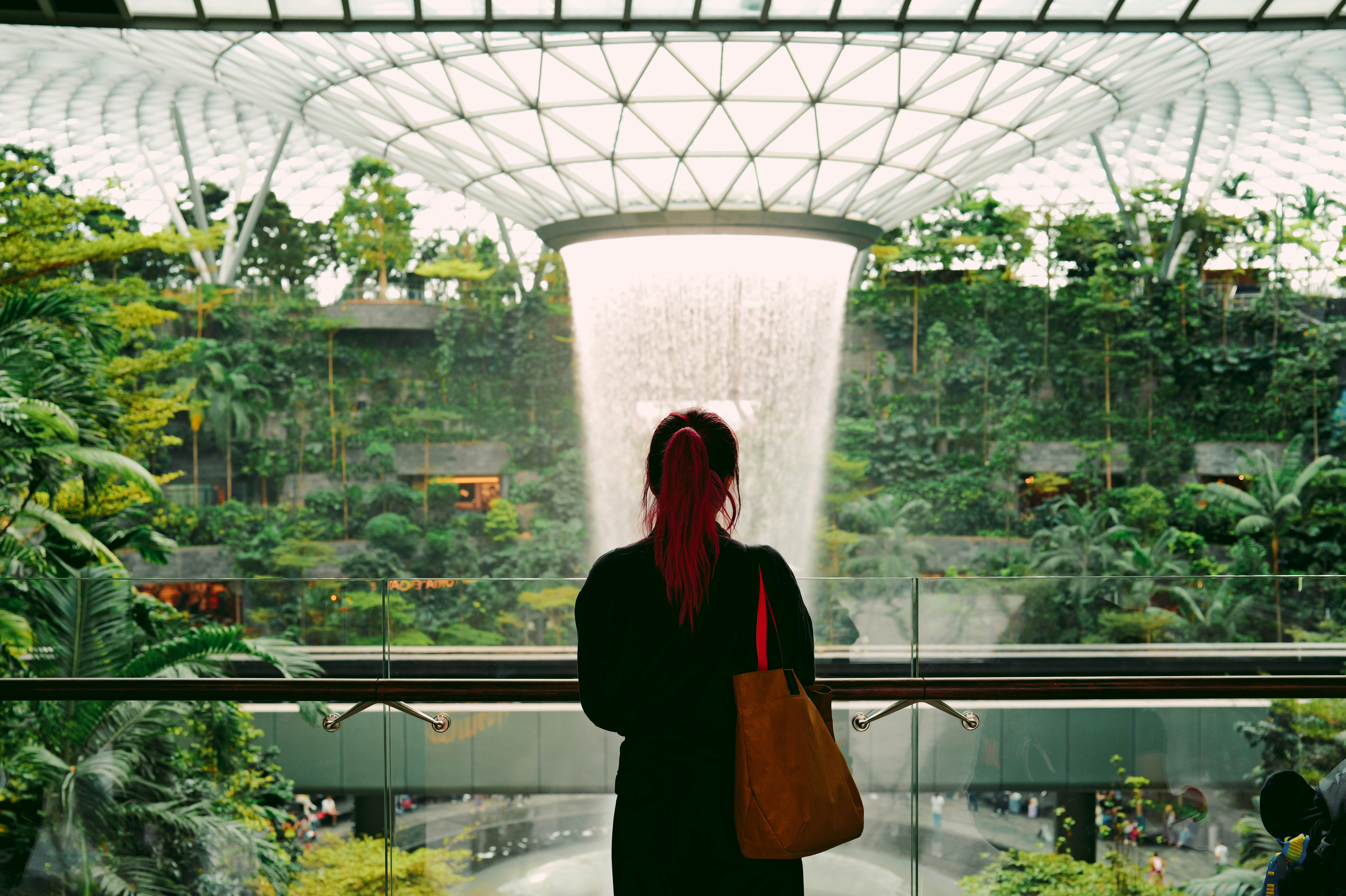 Woman admires indoor waterfall and lush greenery