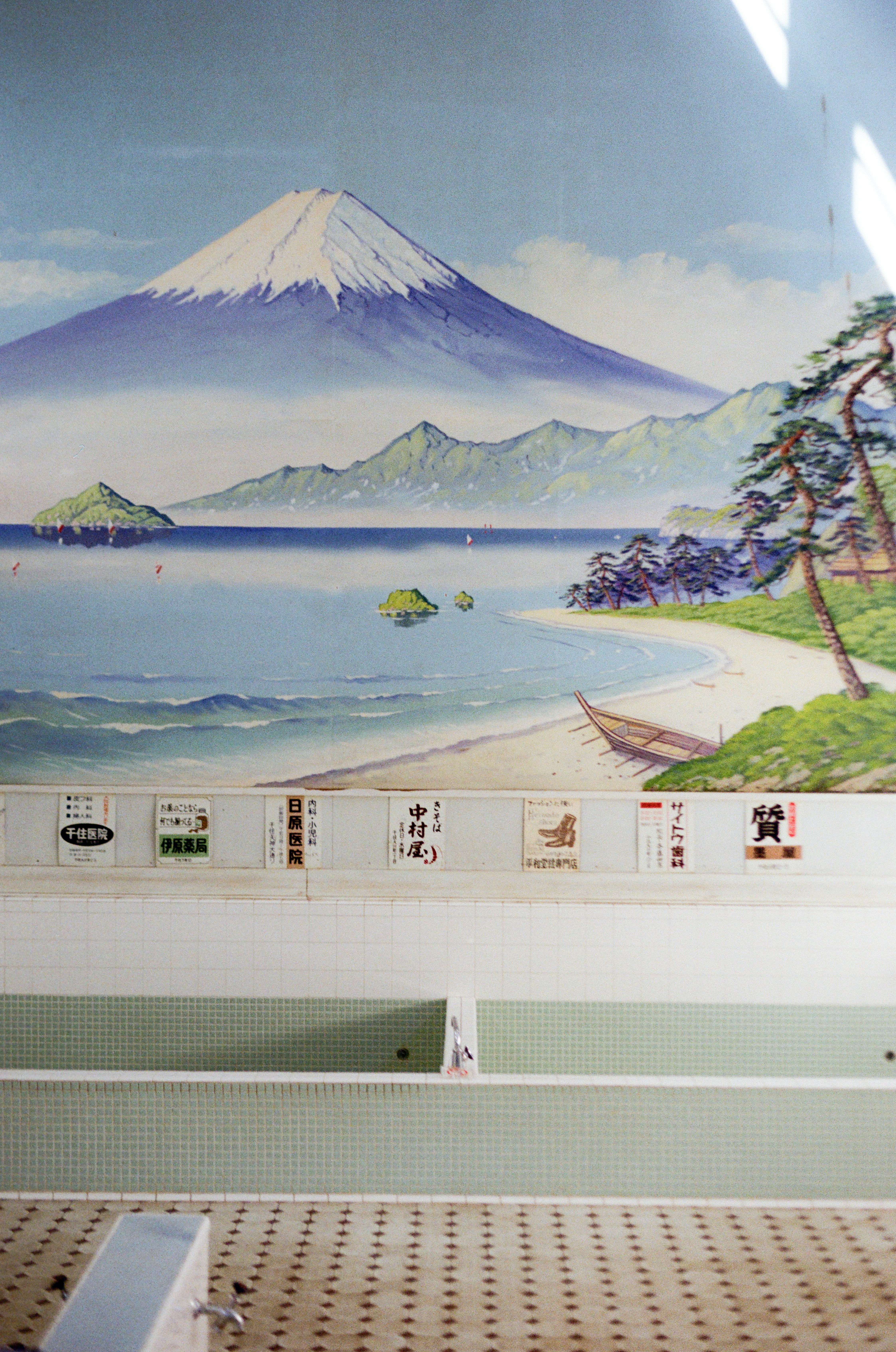 Mount fuji overlooks a serene coastal landscape with a beach.