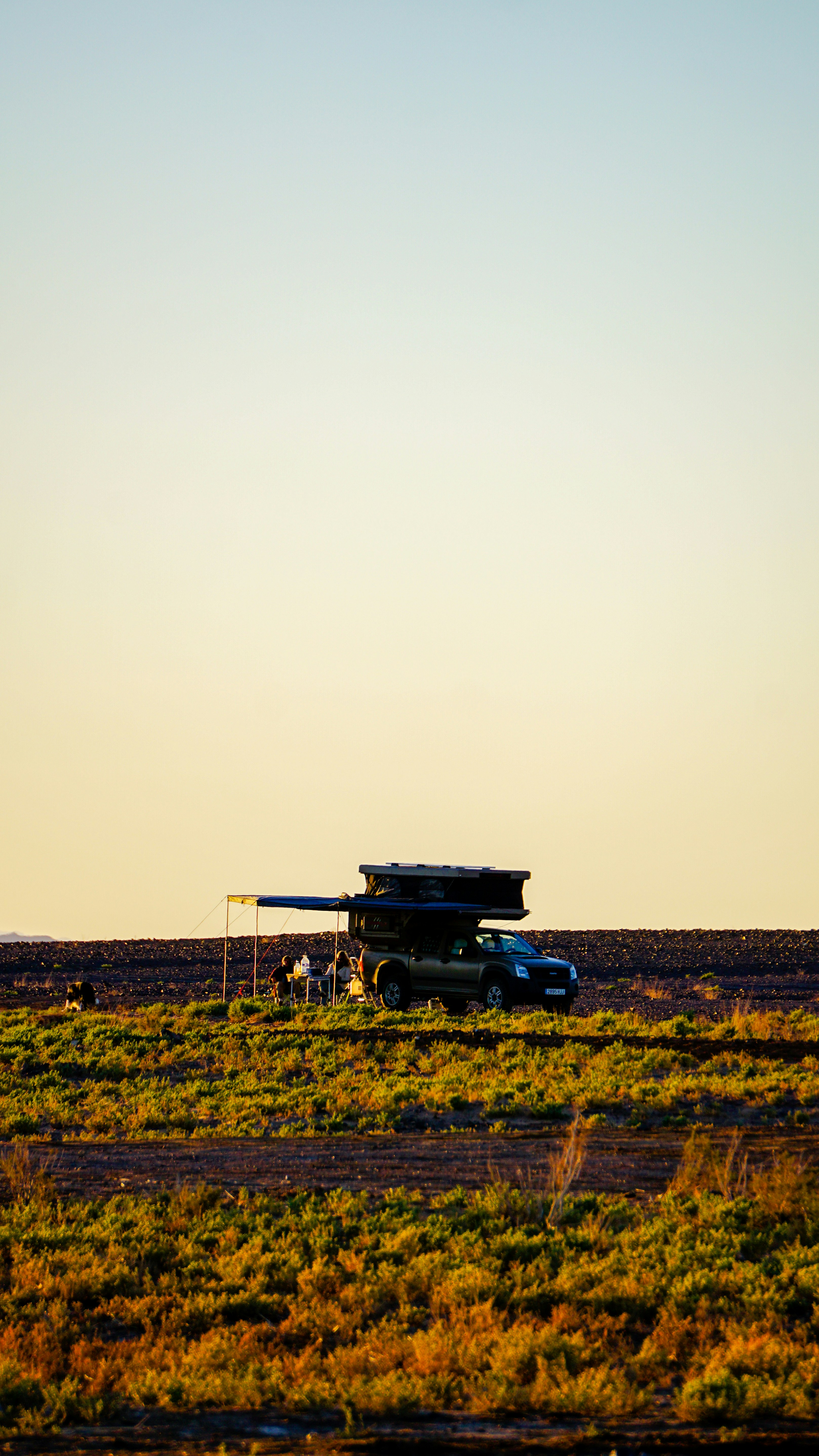 Car with rooftop tent parked in a field at sunset.