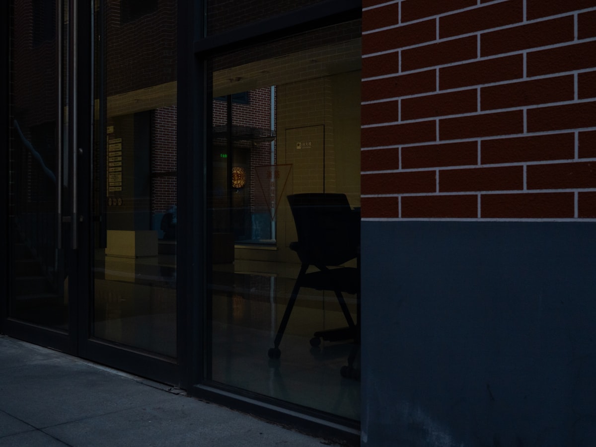 Empty office chair reflected in a glass building facade representing the white-collar job market downturn