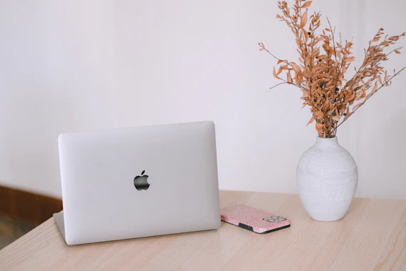 Laptop, phone, and dried flowers on a wooden desk