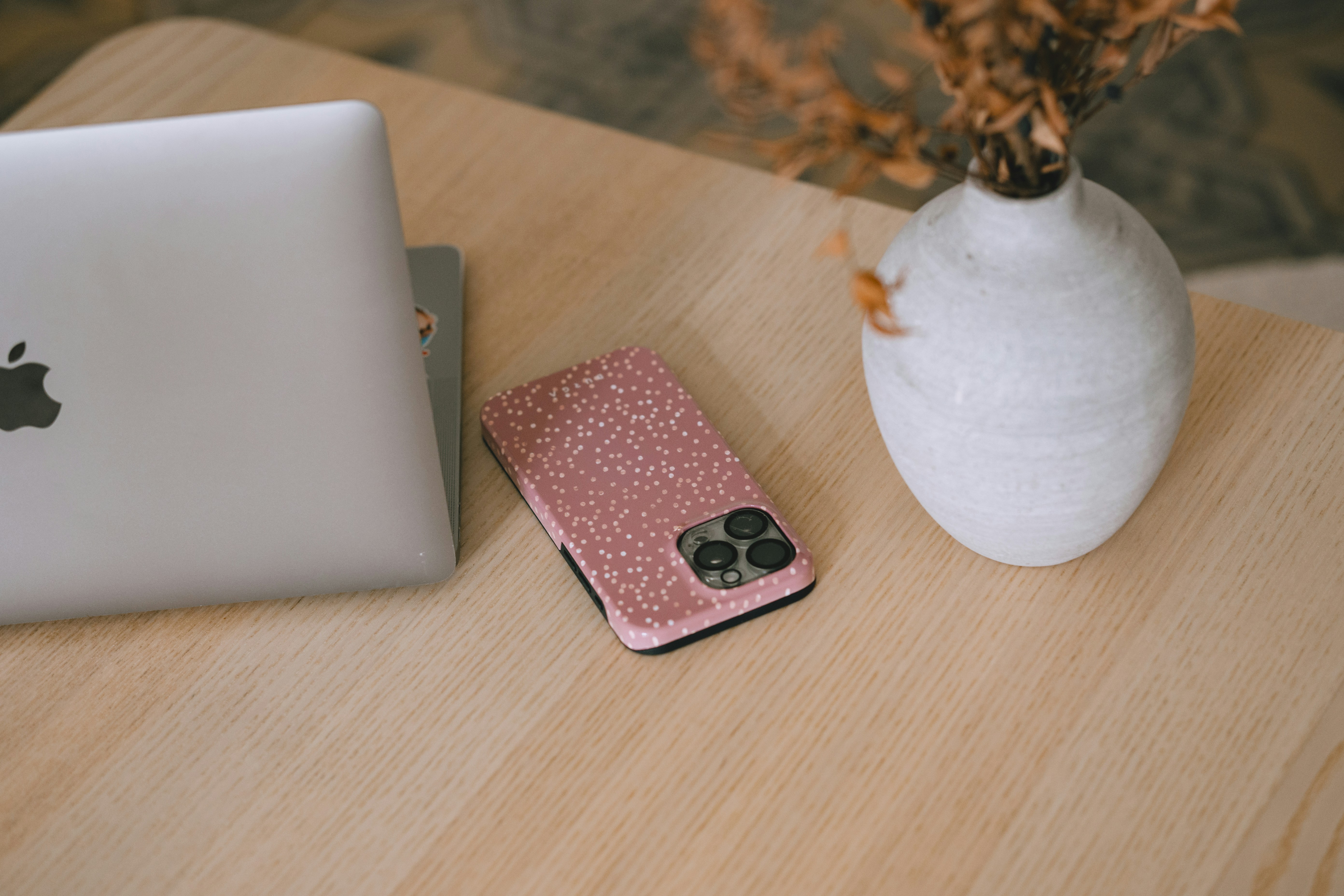 Laptop, phone, and vase on a wooden desk