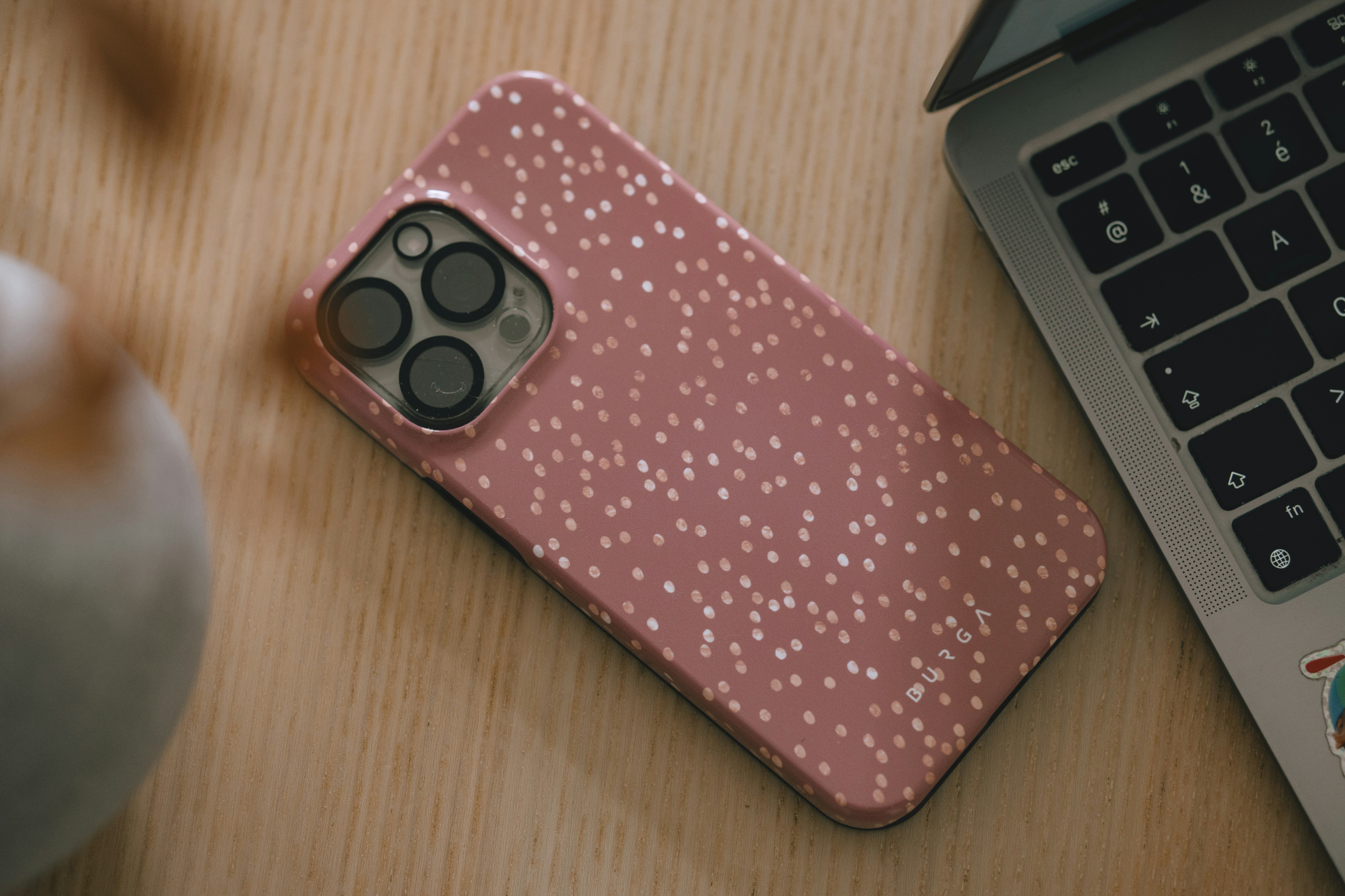 Pink speckled phone case next to laptop