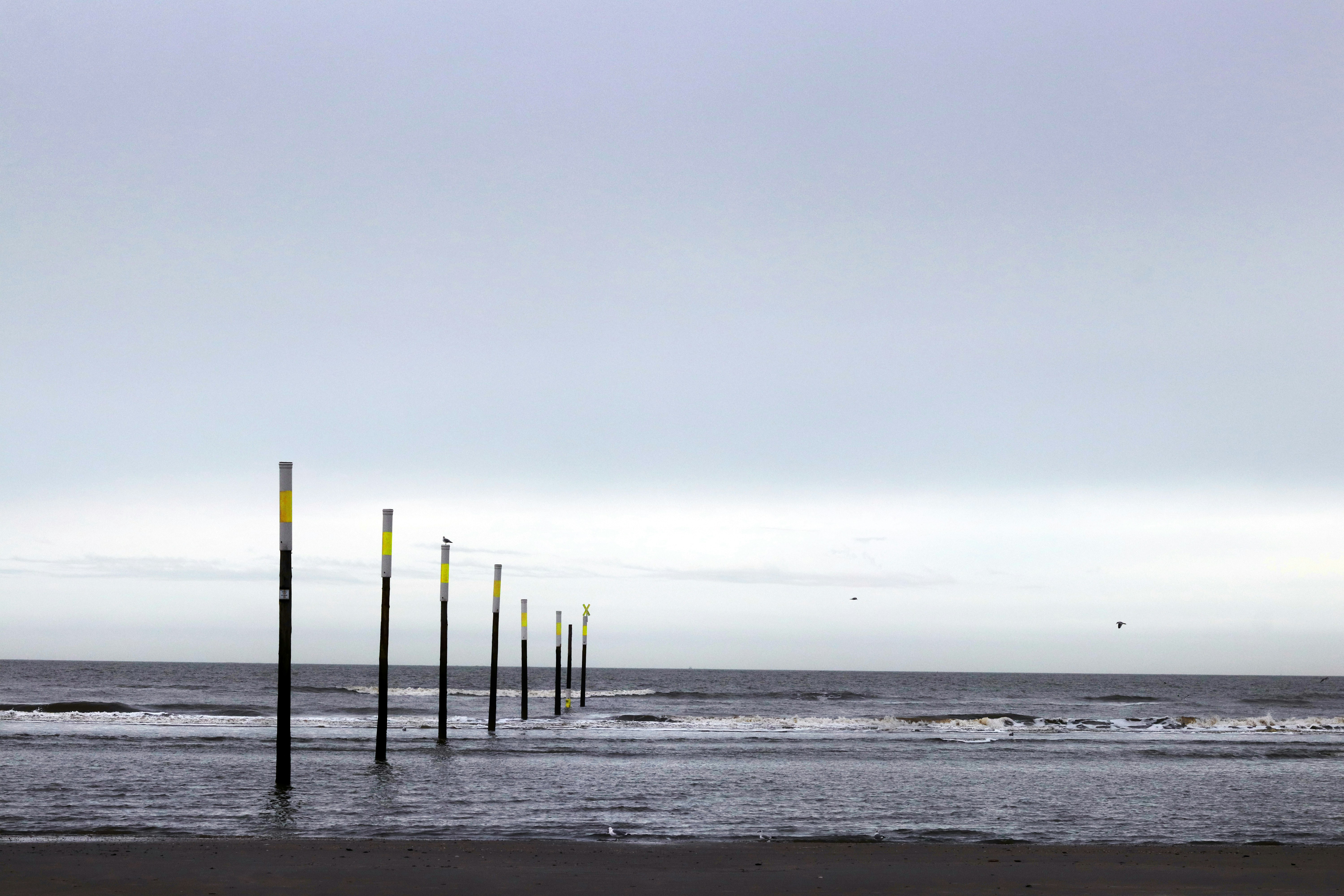 Posts in the ocean with a cloudy sky.