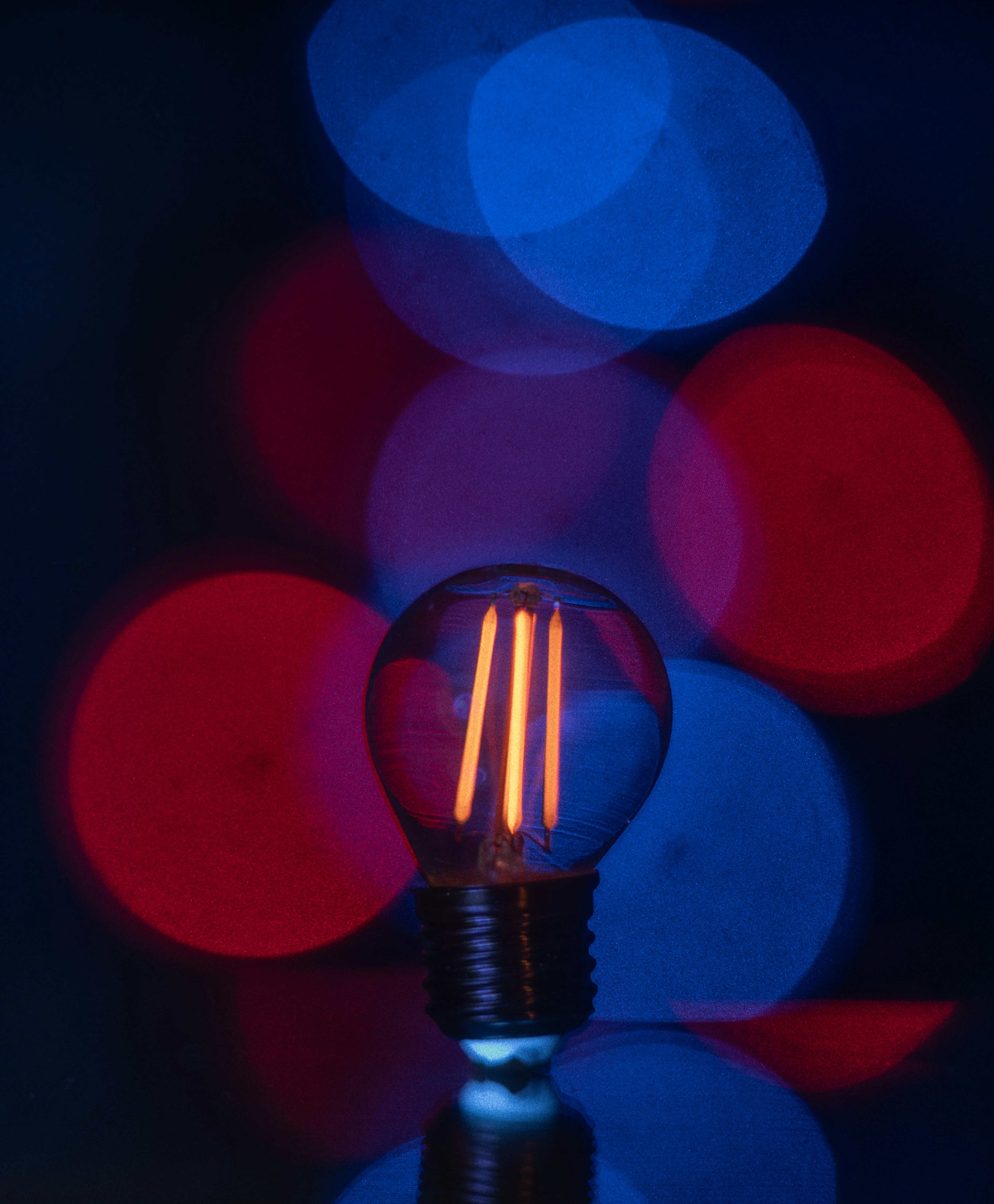 A glowing edison bulb with red and blue bokeh lights.