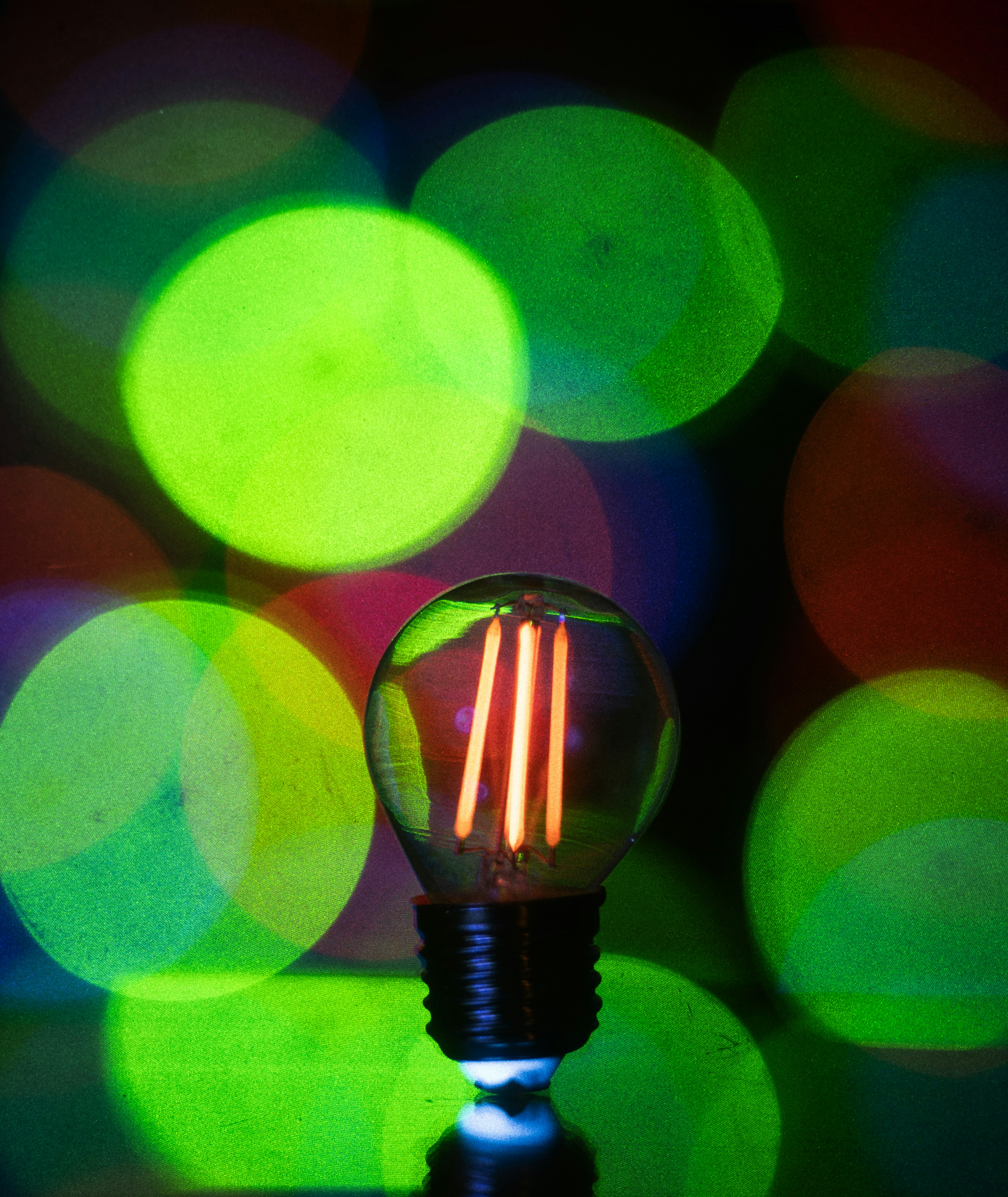 A lit led light bulb with bokeh lights in background.