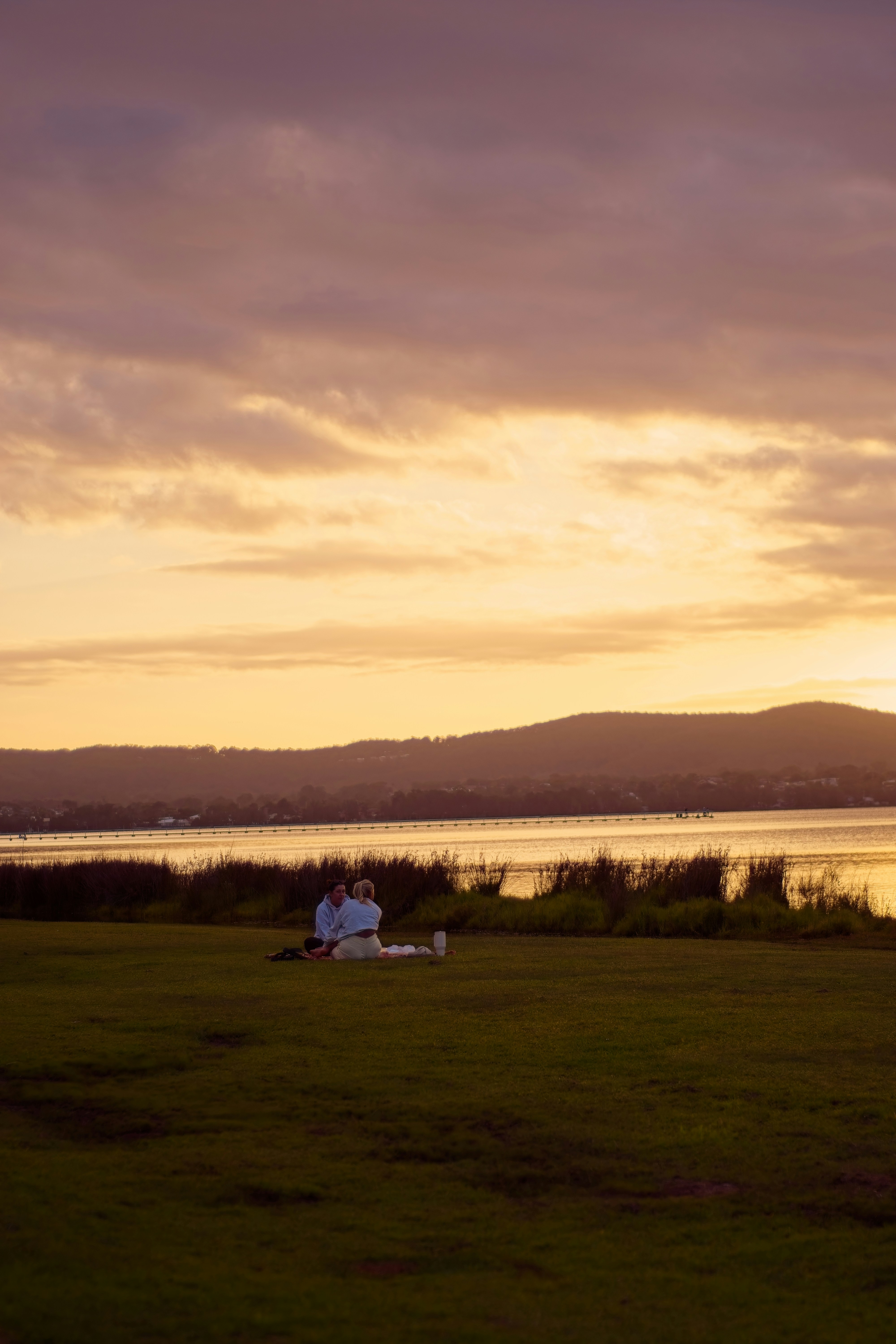 Coppia che si gode un picnic vicino all'acqua al tramonto