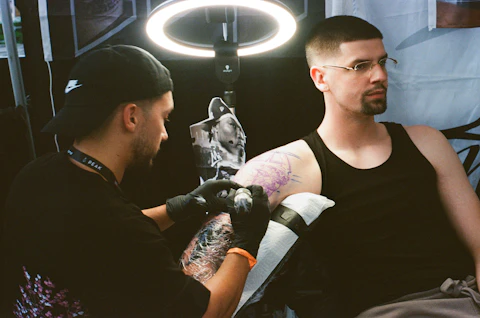 Tatuador trabajando en el brazo de un cliente.