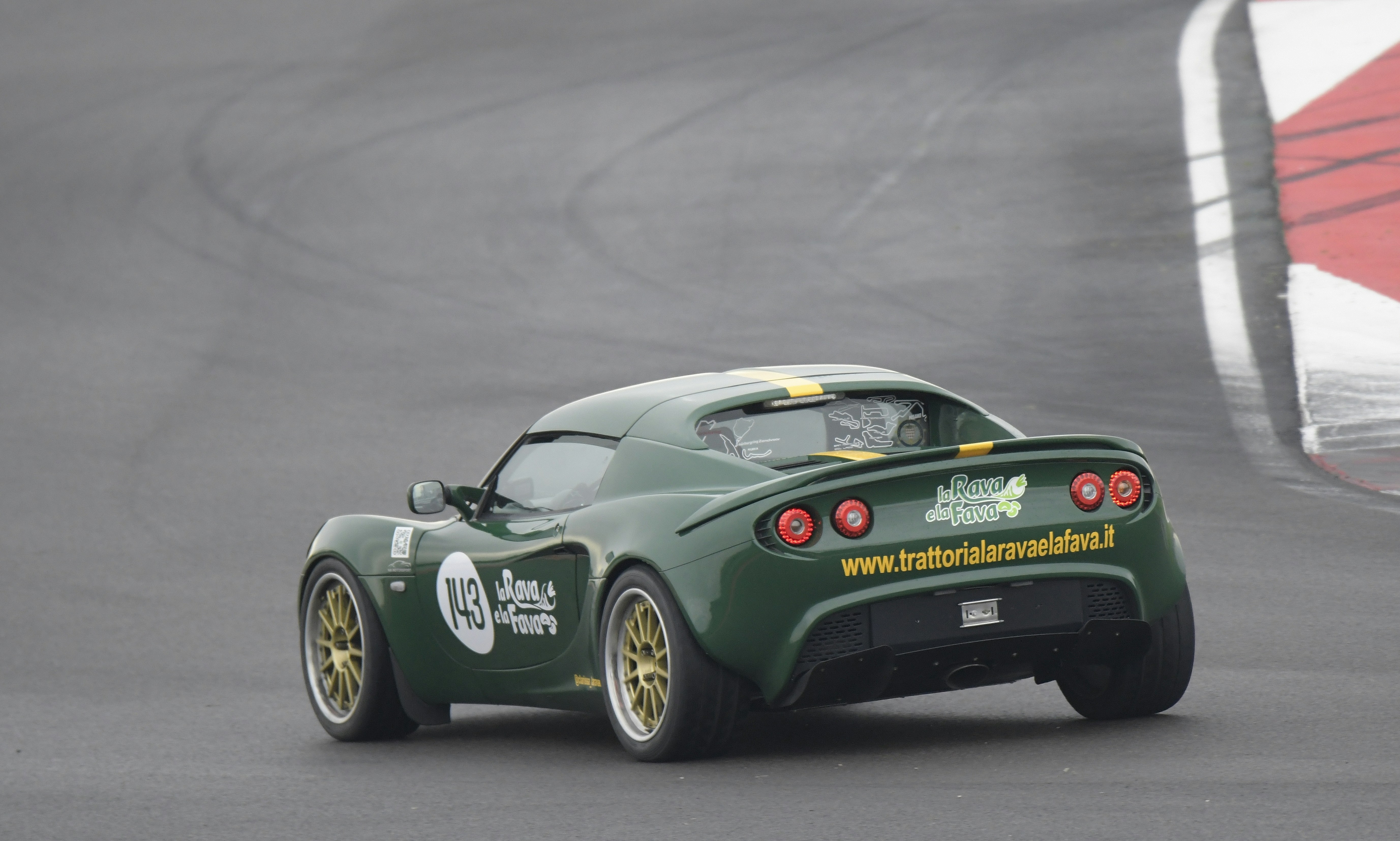 Green race car speeds around a track.